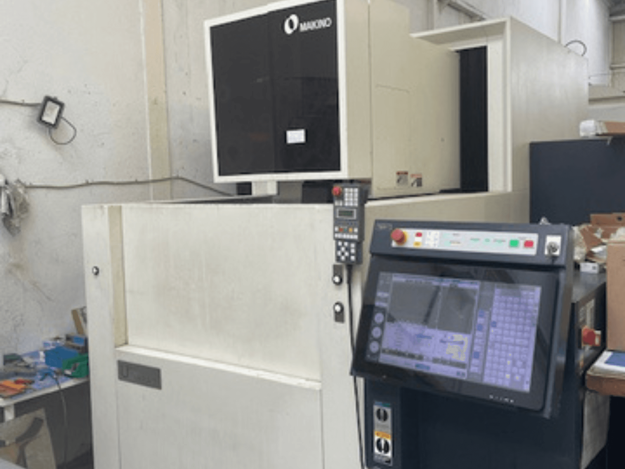 Bir atölyedeki Makino U6 HEAT tel EDM makinesi, kontrol panelini ve dijital ekranı gösteren önden görünüm.