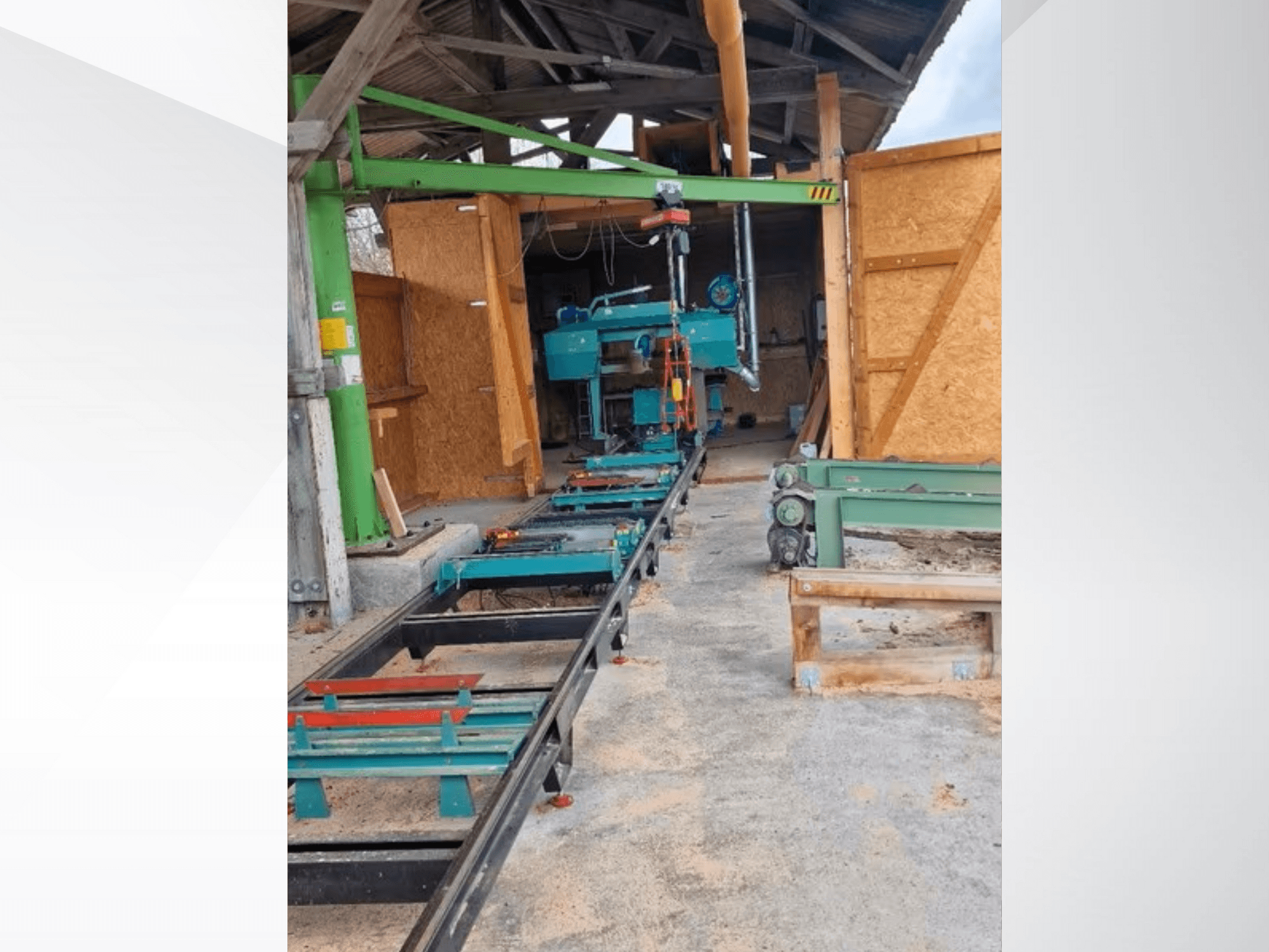 Atölyede yatay şerit testere makinesi, önden görünüm. Ekipman bir palet ve ek yeşil aksesuarlar içerir.