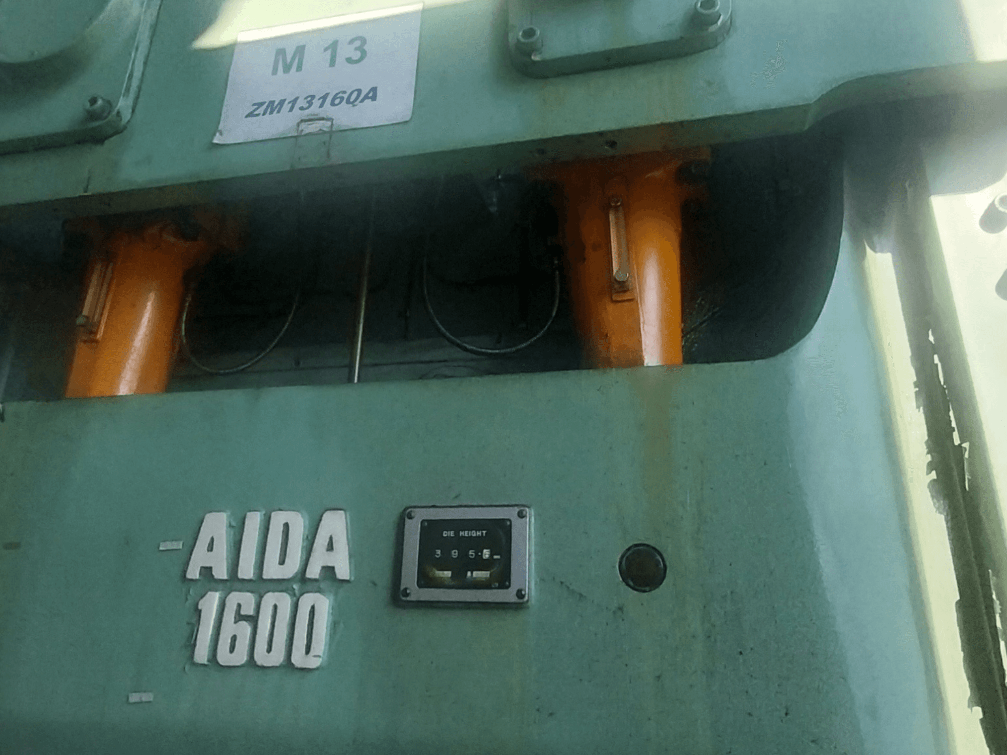 AIDA NC2-1600 mekanik damgalama presi, önden görünüm; turuncu hidrolik bileşenler ve kalıp yükseklik göstergesi görülebilir.
