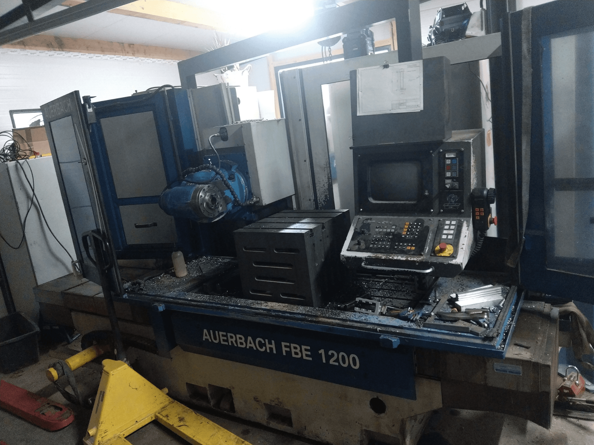 Auerbach FBE 1200 metal delme makinesi, önden görünüm, kontrol panelini, motoru ve çalışma yüzeyindeki metal talaşlarını gösteriyor.