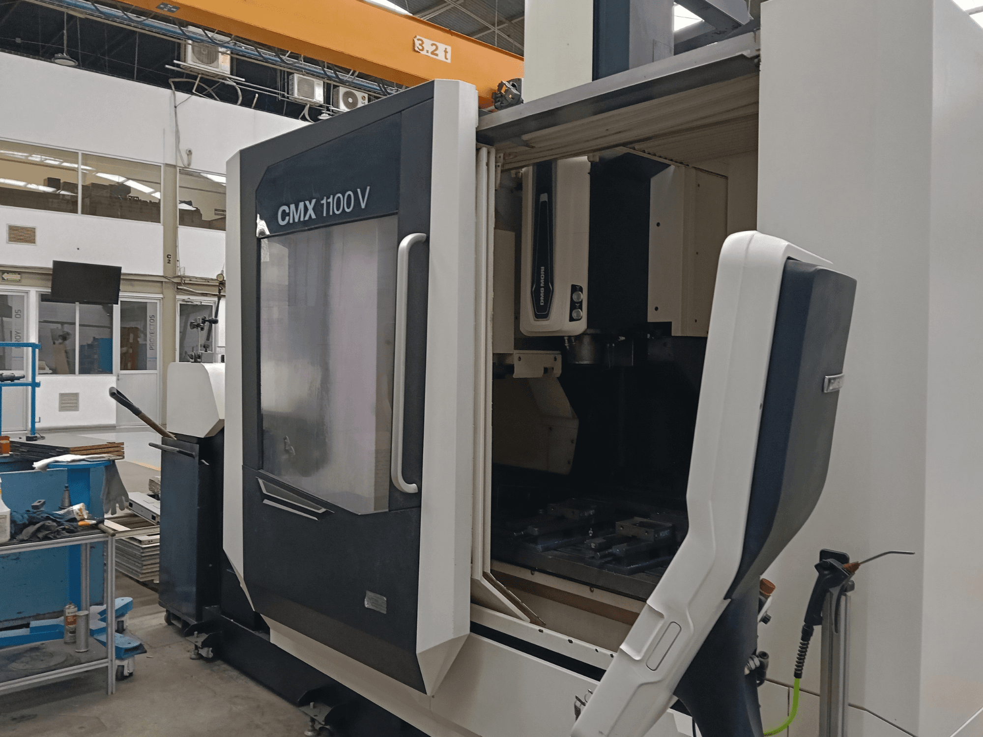 DMG MORI CMX 1100 V dikey işleme merkezi; endüstriyel bir alanda, kapısı açık ve iç kısımdaki takım düzenlemesi görülebilen önden görünüm.