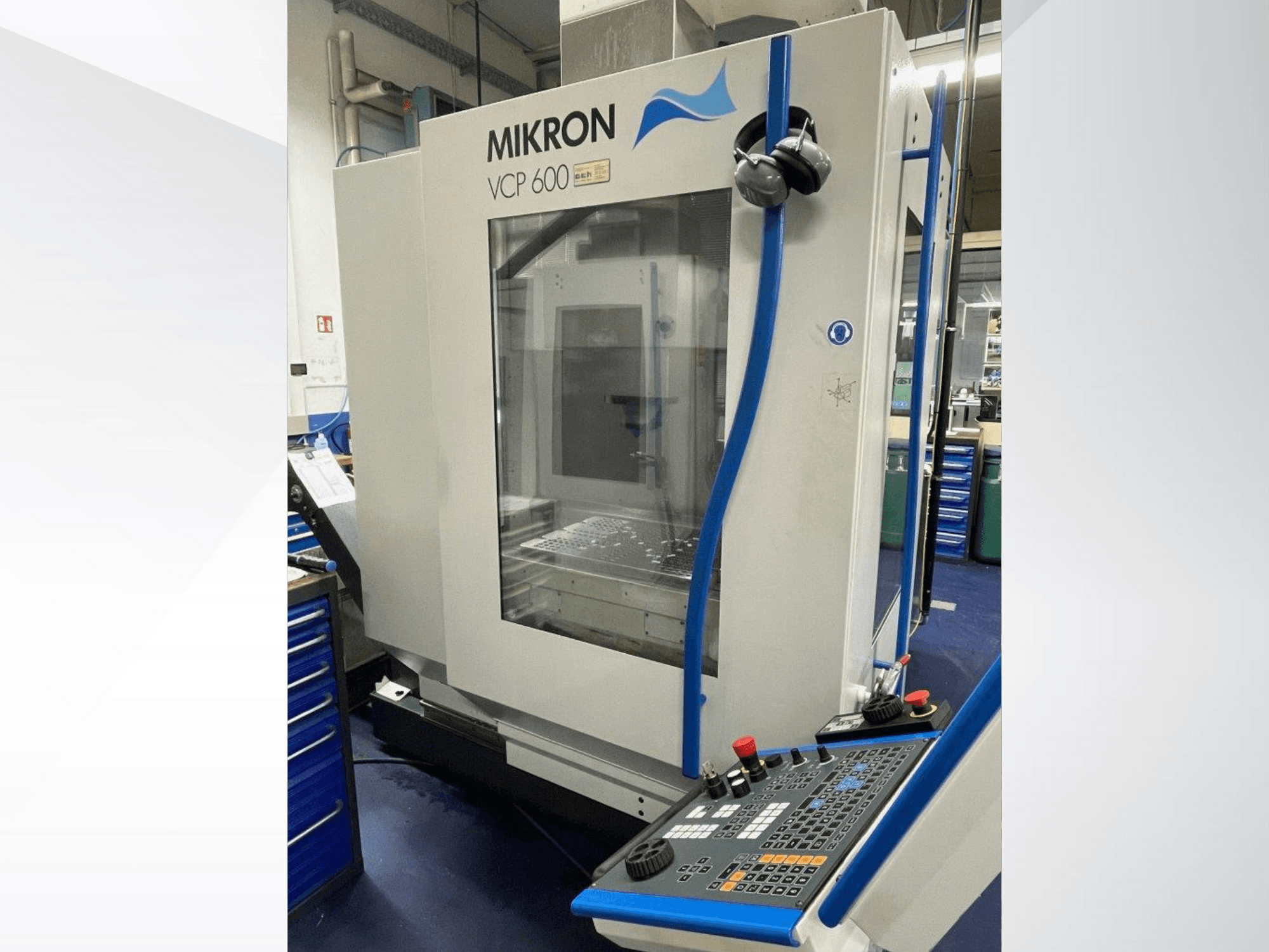 Mikron VCP 600 işleme merkezi bir atölyede, önden görünüm, düğmeler ve topuzlar içeren bir kontrol paneli ile.