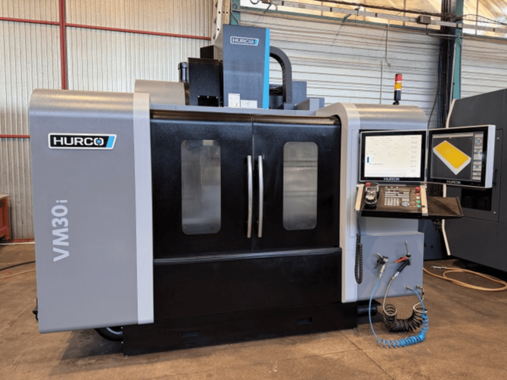 Hurco VM30i Dikey İşleme Merkezi, kontrol panelini, ekranları ve makine kapaklarını gösteren önden görünüm.