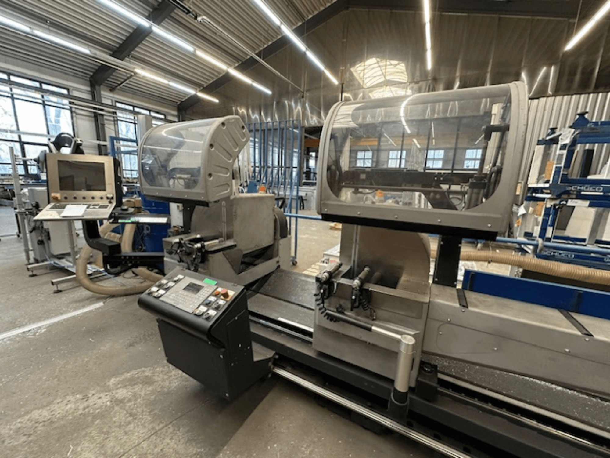 SCHÜCO PDG E CUT dairesel metal testeresi, önden görünüm, kontrol paneli, koruyucu kapaklar ve atölye ortamında kesim alanı.