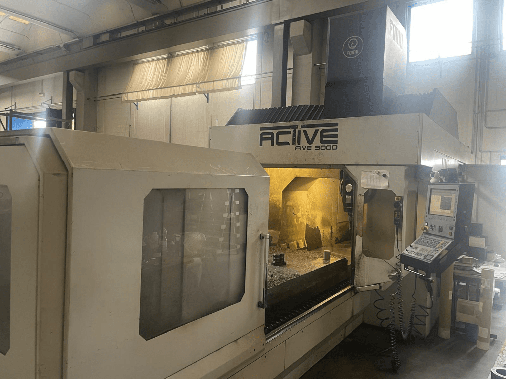ACTIVE Five 3000 CNC makinesinin önden görünümü, kontrol panelini ve içinde kısmen işlenmiş parça bulunan çalışma alanını göstermektedir.