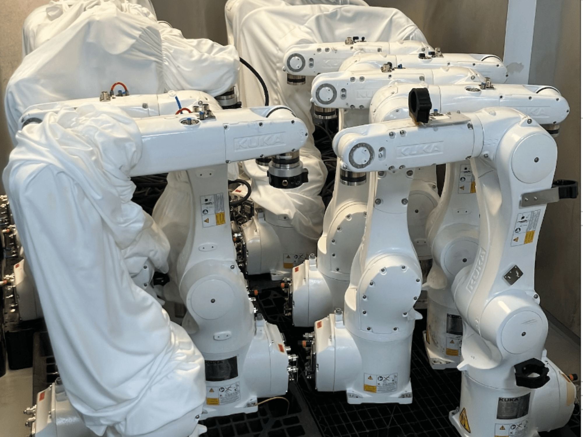 Kısmen kumaş kaplı KUKA KR 10 R900-2 robot kolları, önden bakıldığında şık beyaz tasarımlarını ve teknik detaylarını sergiliyor.