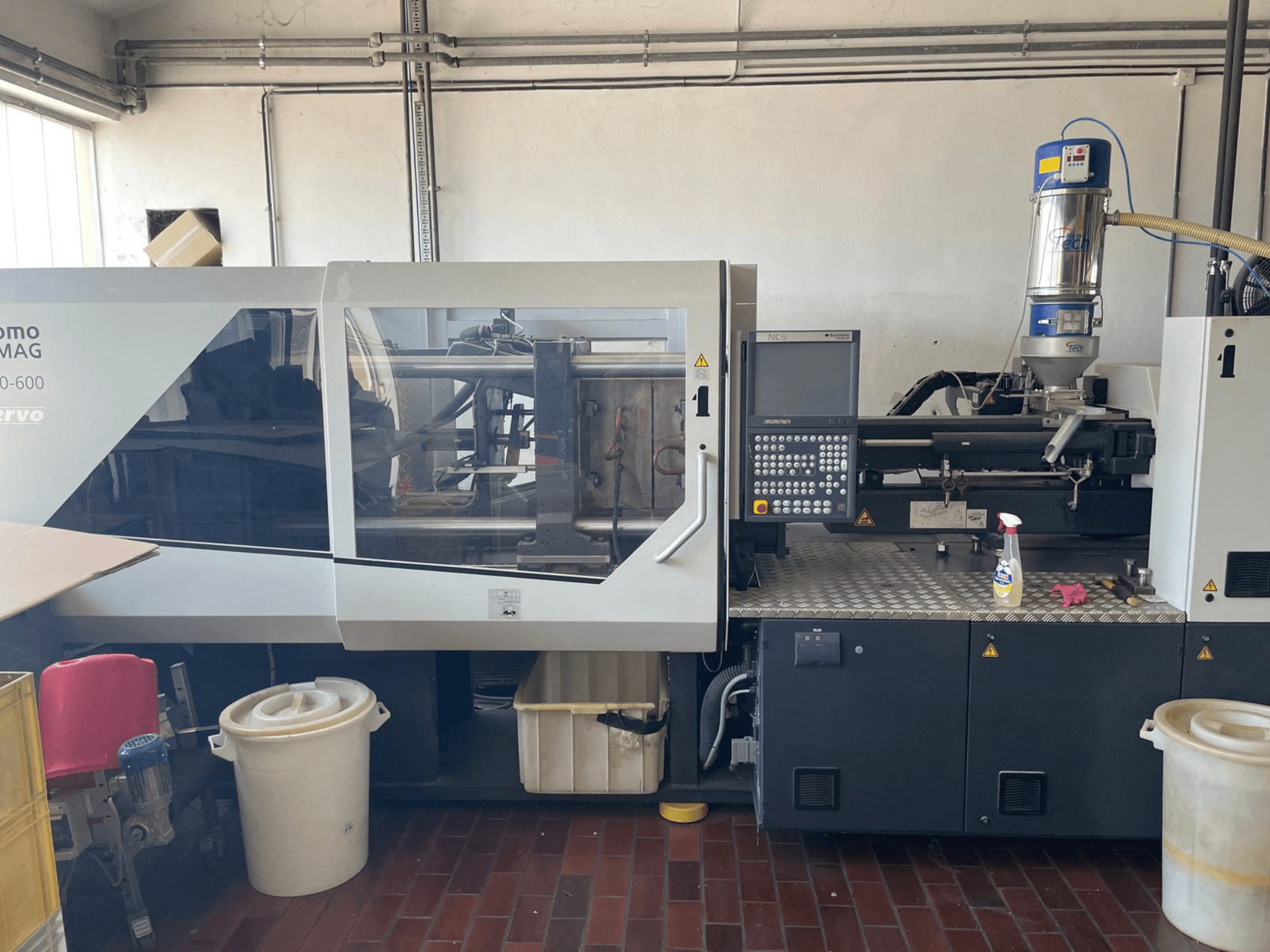 SUMITOMO SHI DEMAG Systec 160/520-600 hidrolik enjeksiyon kalıplama makinesinin kontrol paneli ve besleme ünitesi ile önden görünümü.