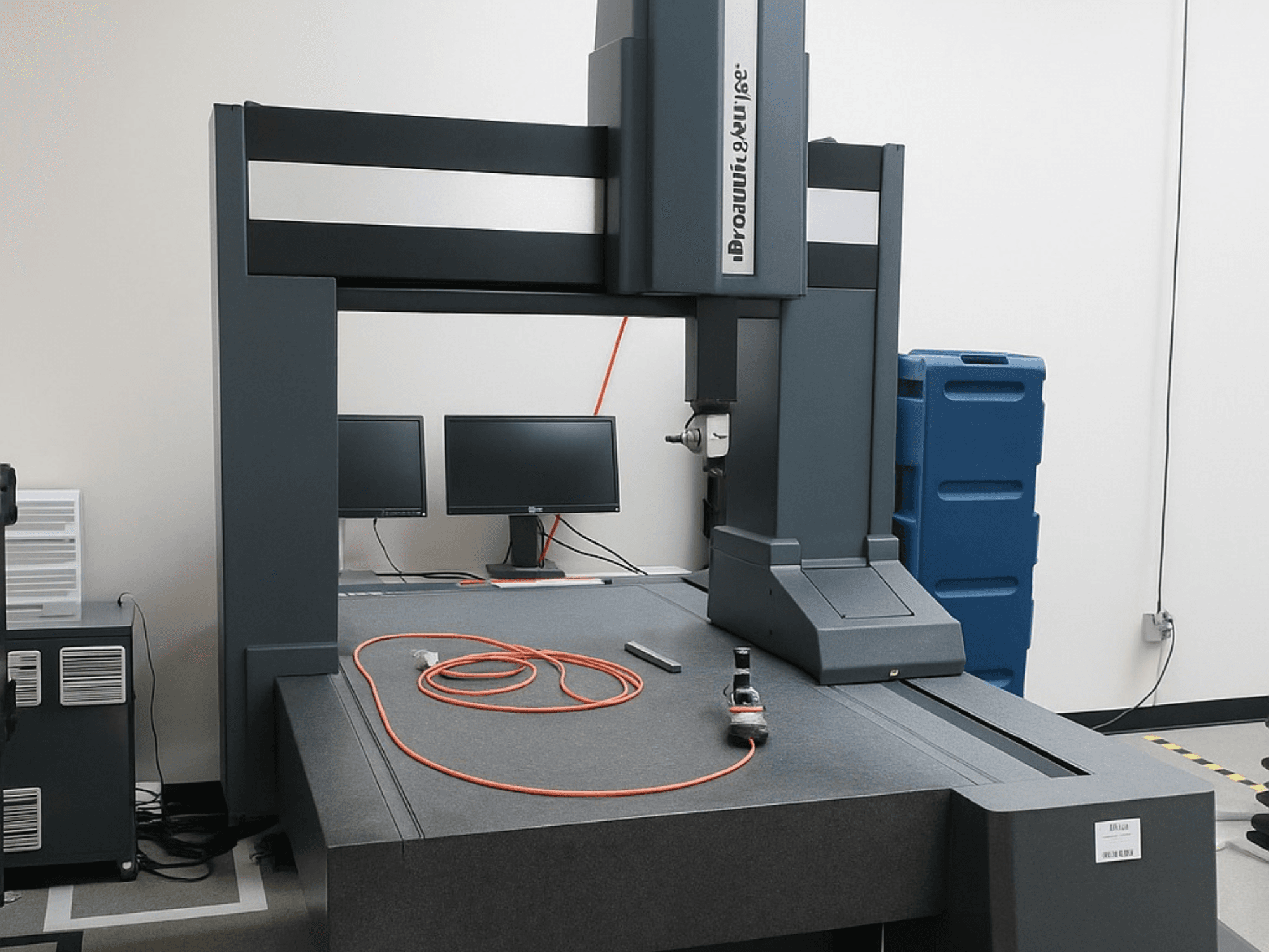 Brooks Automation iki monitörlü koordinat ölçüm cihazı, önden görünüm, gri bir masa üstü ve ölçüm aletlerine sahiptir.