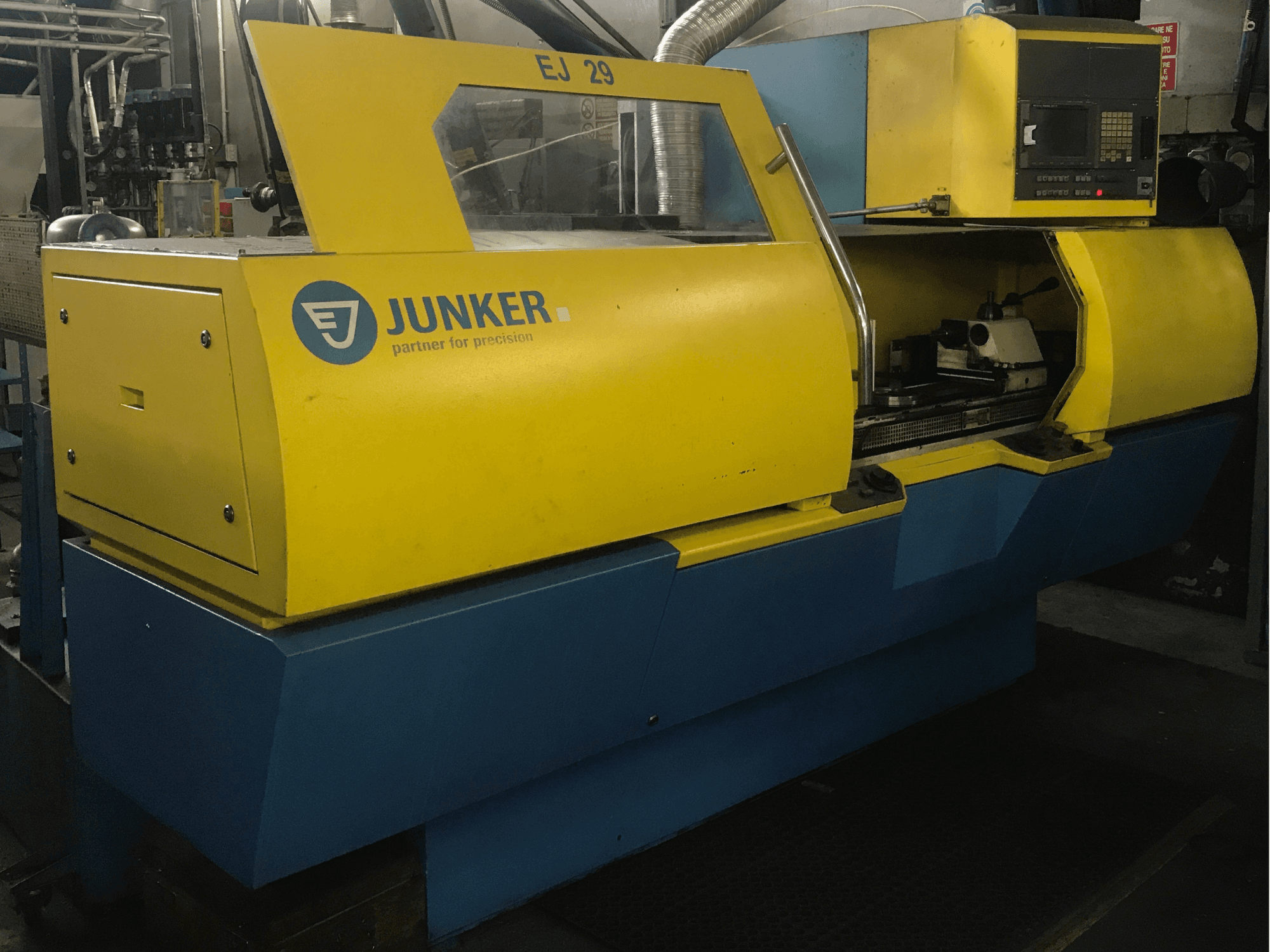 JUNKER EJ 29 taşlama makinesi, önden görünüm, sarı ve mavi gövde, kontrol paneli ve görünür iç bileşenlere sahiptir.