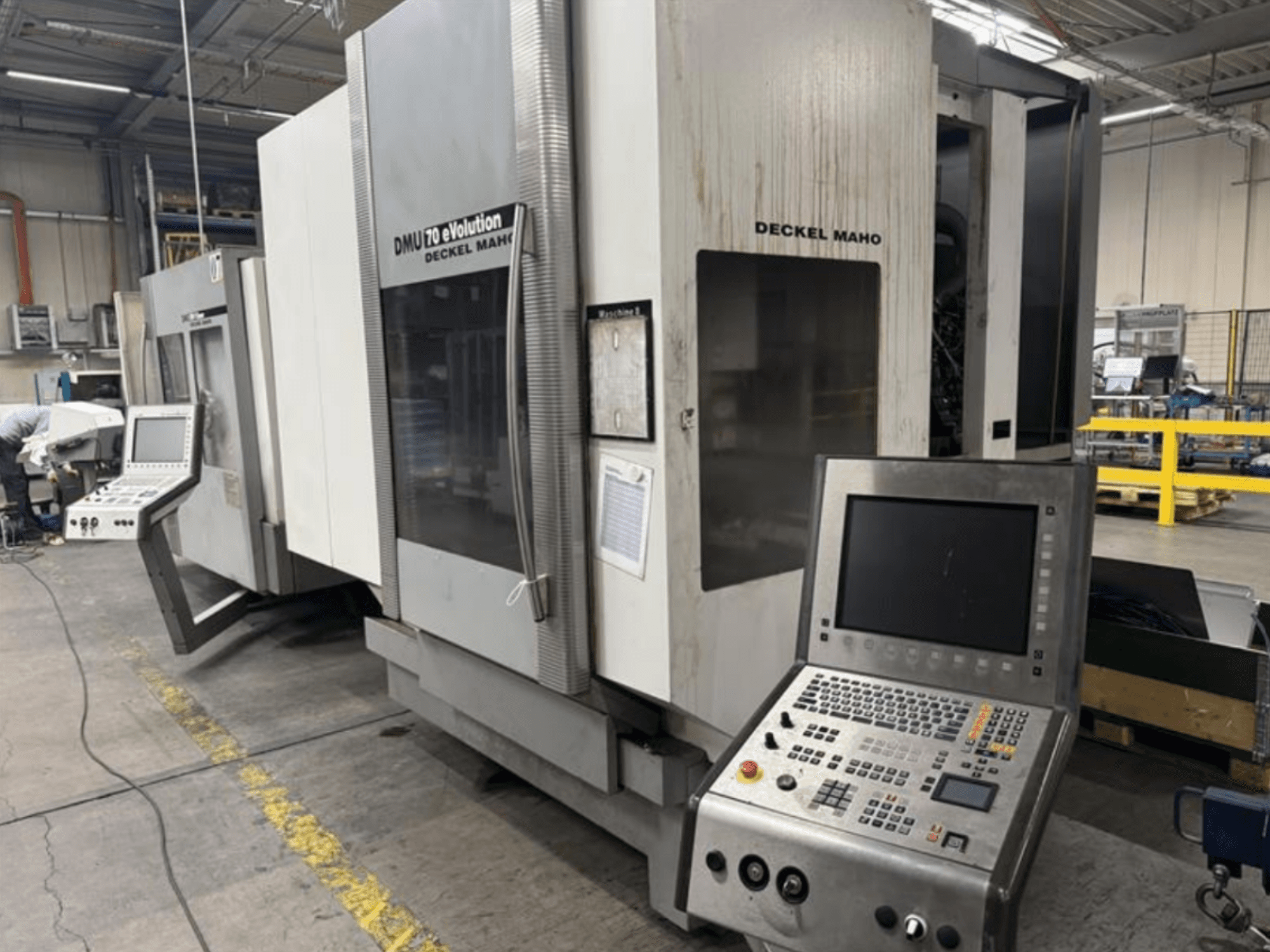 Bir üretim tesisinde bulunan kontrol panelli bir Deckel Maho DMU 70 eVOLUTION CNC makinesinin önden görünümü.