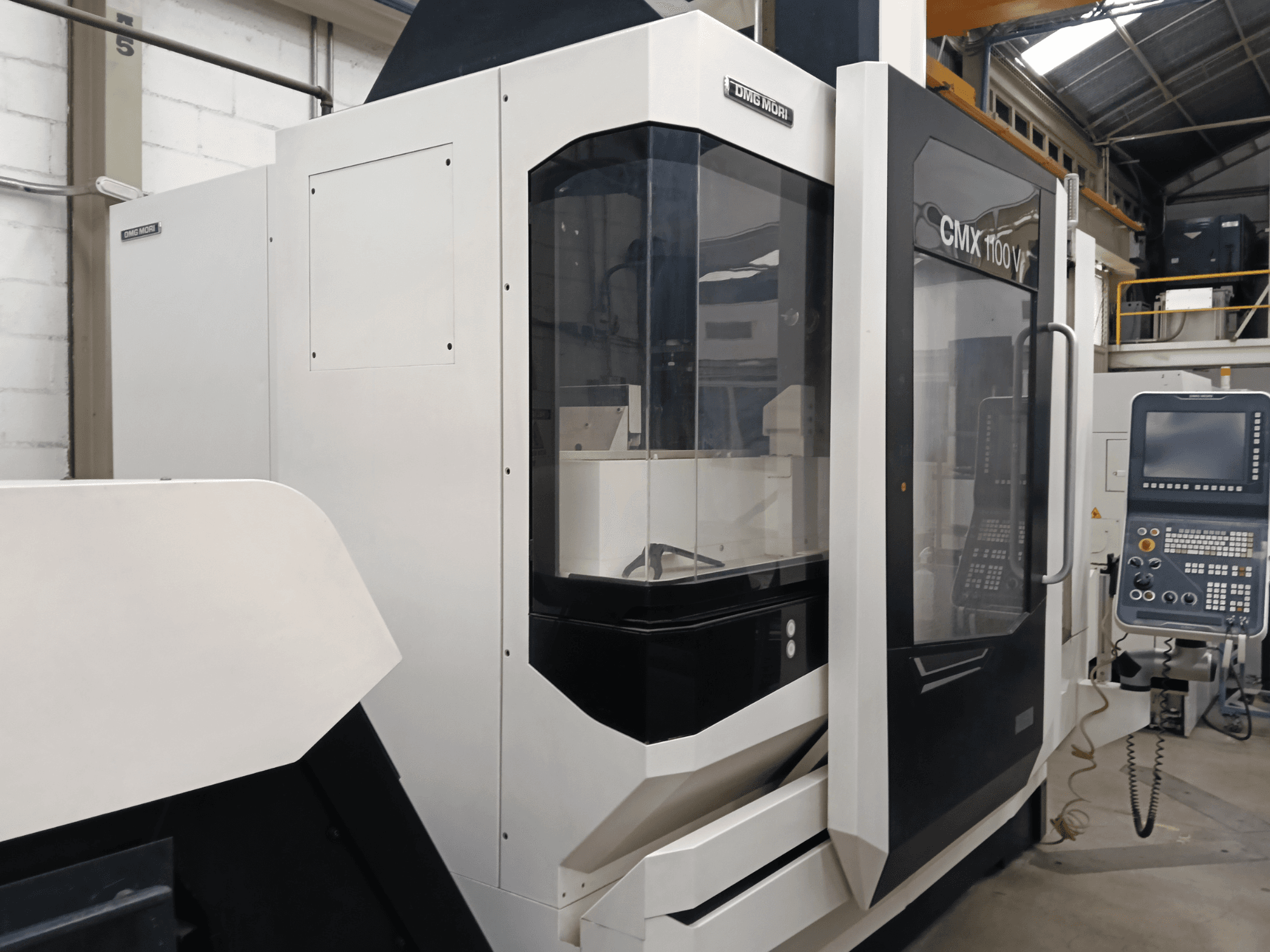 DMG MORI CMX 1100 V dikey işleme merkezi, önden görünüm; kontrol paneli ve cam muhafaza görülmektedir.