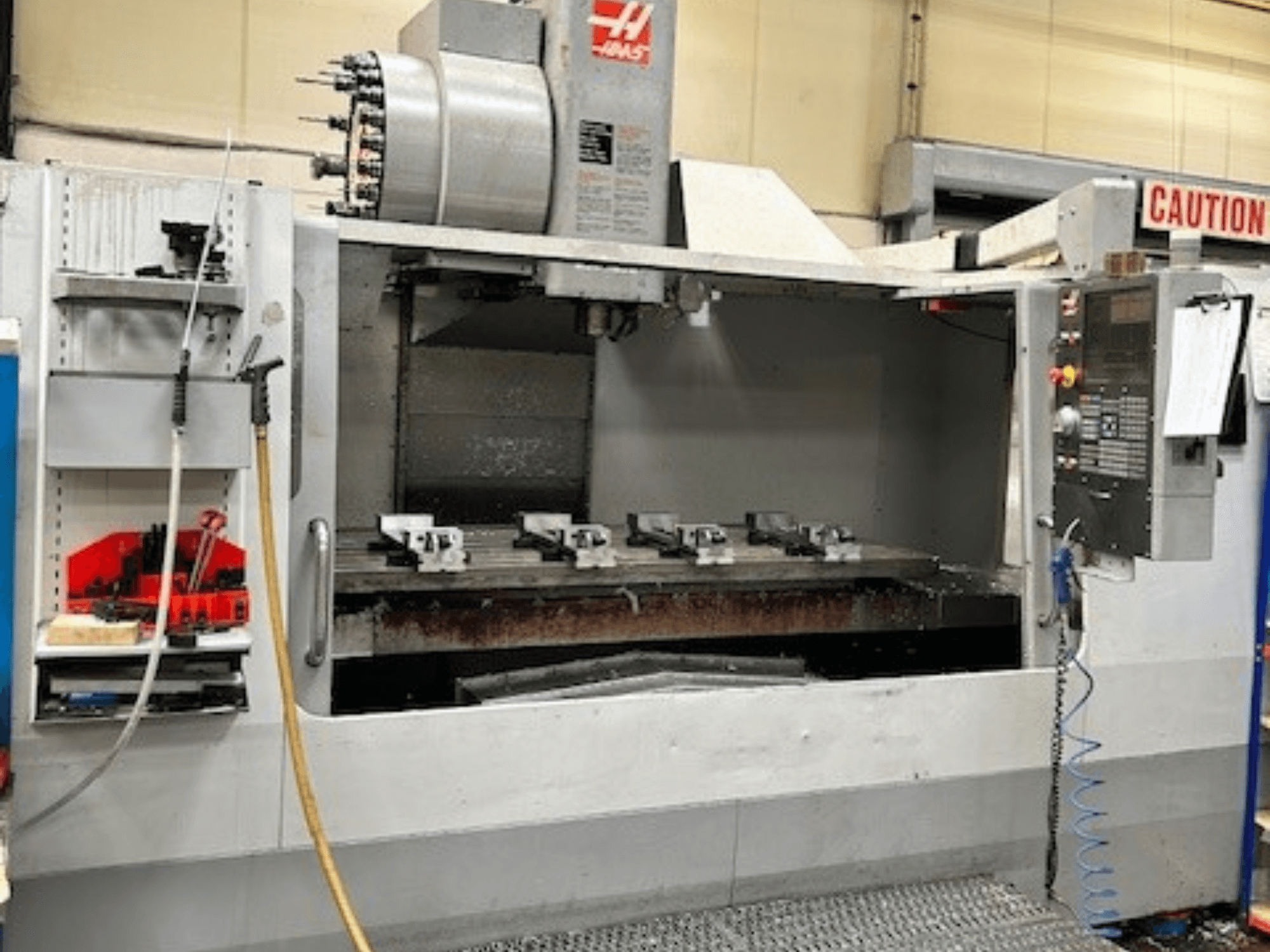 HAAS VF-9/40HE dikey işleme merkezi, önden görünüm, takım tutucu ve aksesuarlar yandan görülebilir.