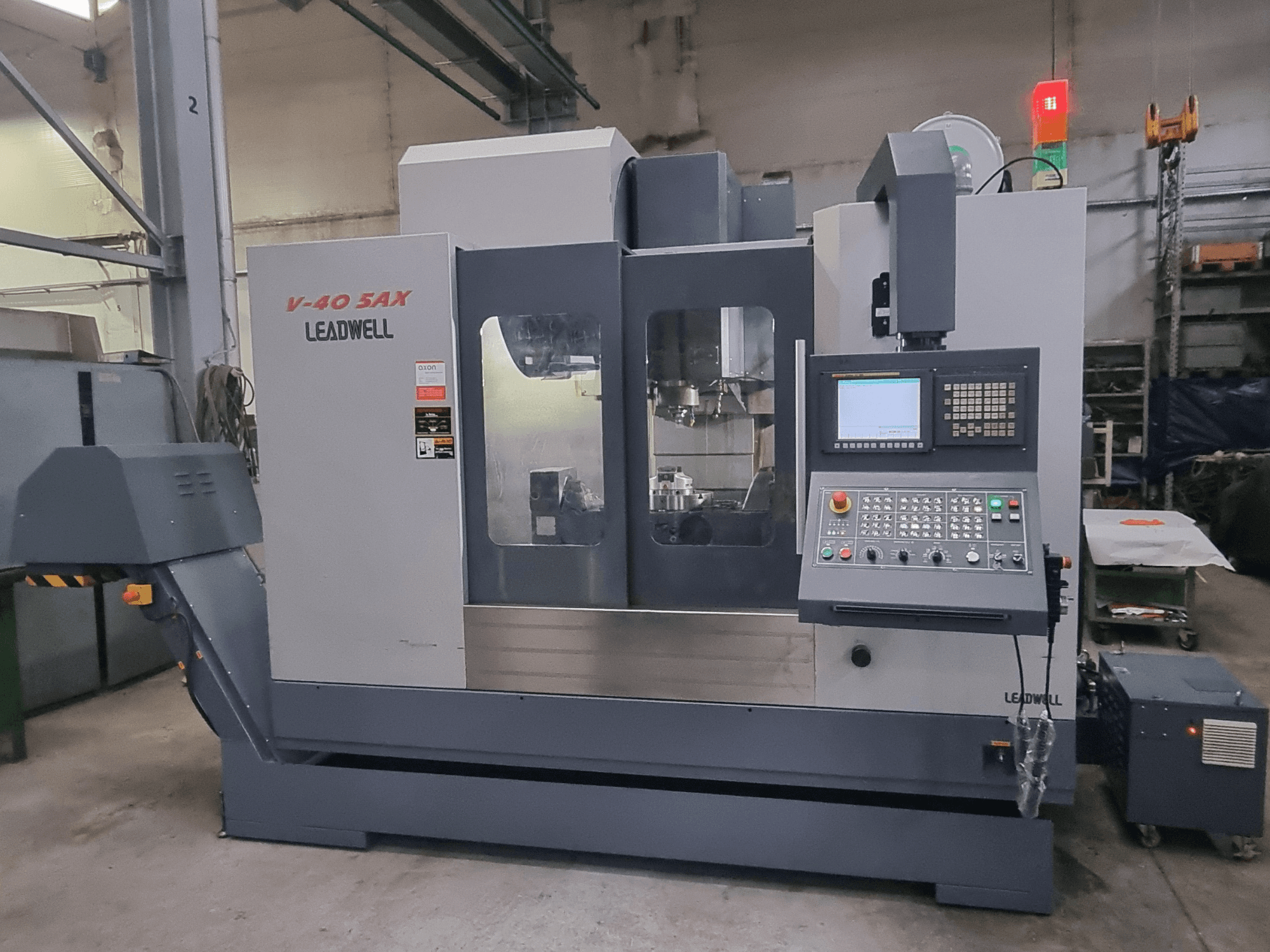 Leadwell V40 5AX dikey işleme merkezi, önden görünüm; kontrol paneli ve güvenlik ışıklarıyla donatılmış işleme alanı gösterilmektedir.