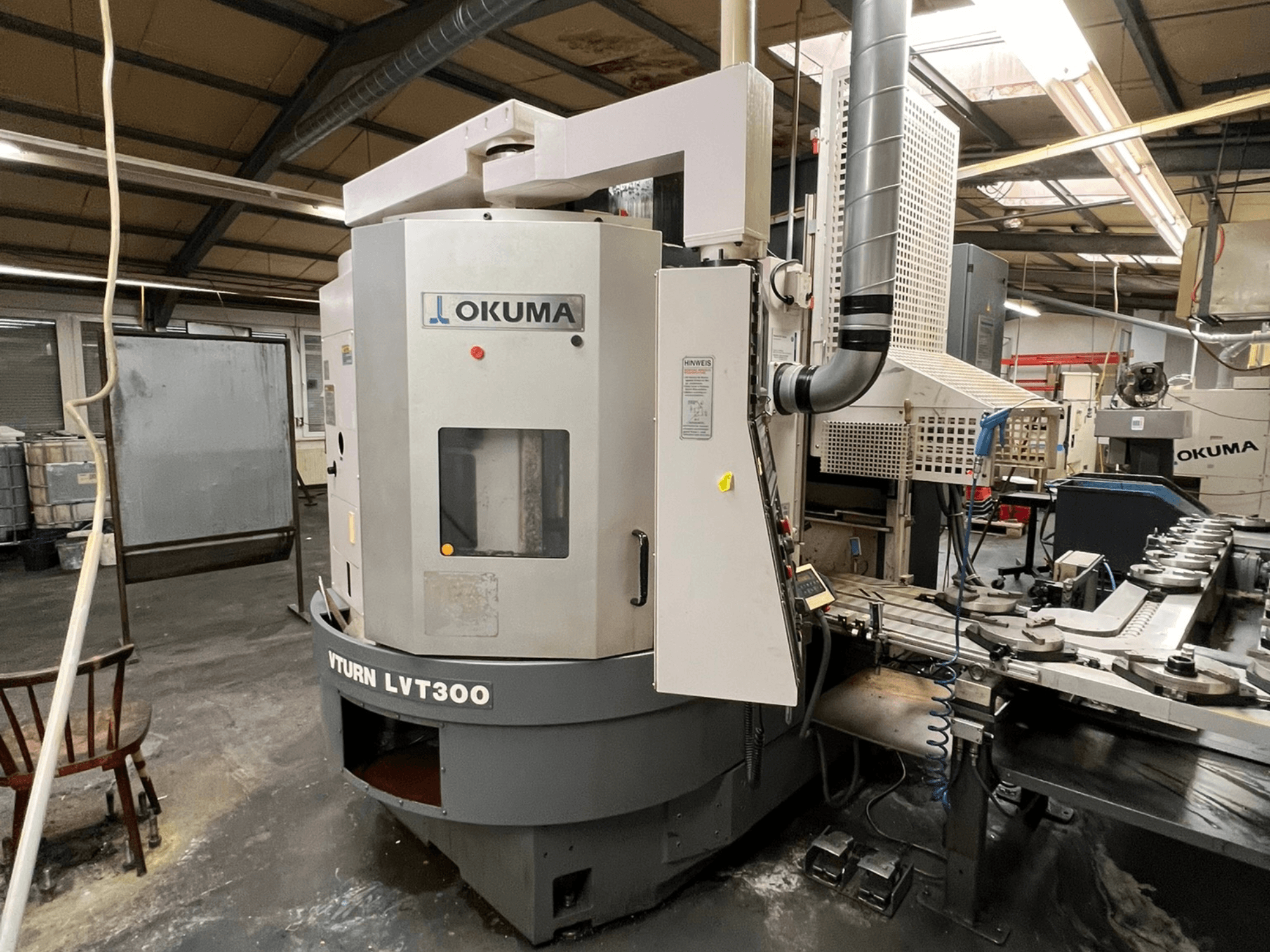 Okuma Vturn LVT300 CNC torna tezgahı, endüstriyel ortamda yandan görünüm, kontrol paneli ve soğutma sıvısı sistemi.