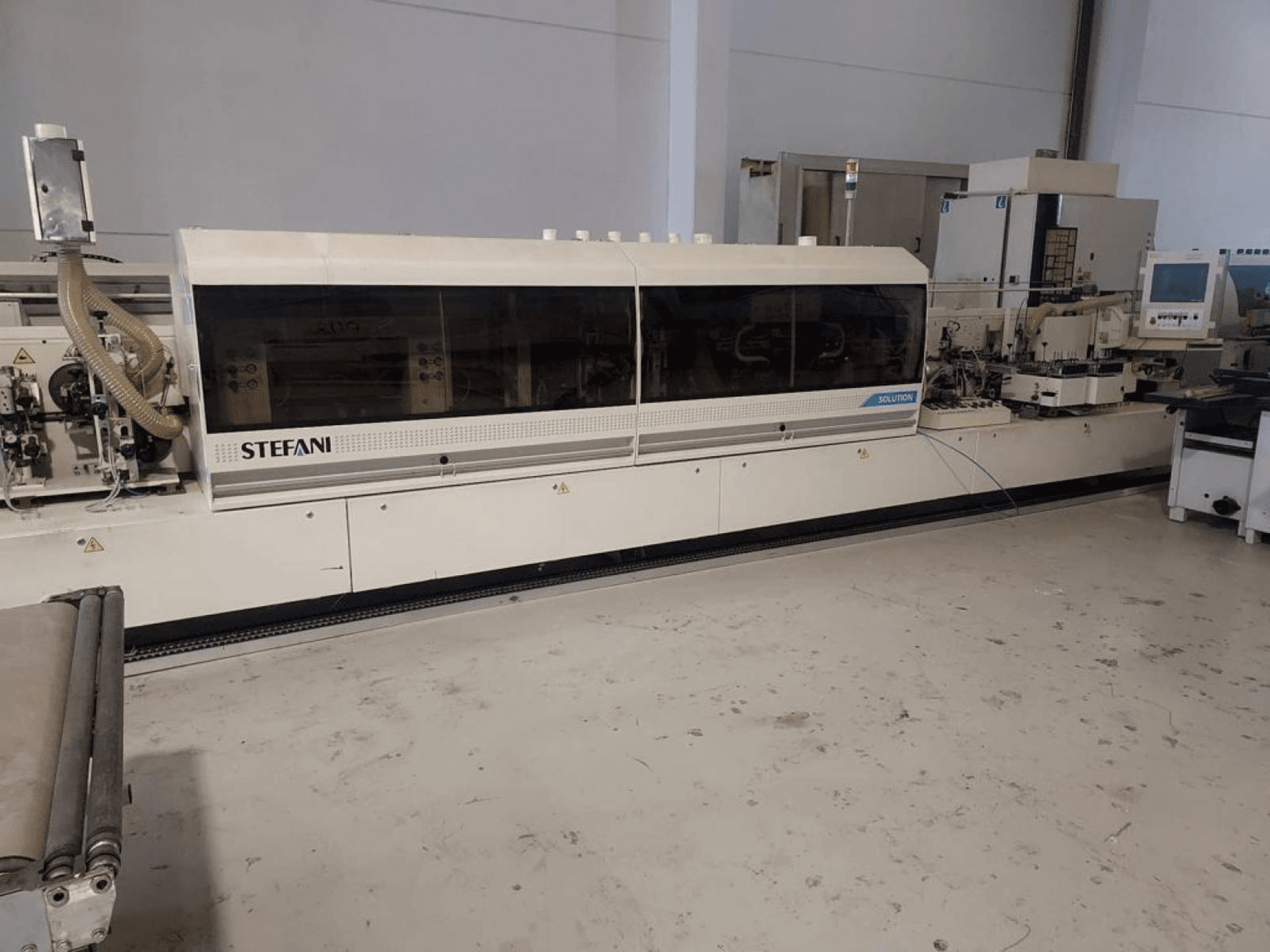 Stefani Solutions kenar bantlama makinesi, önden görünüm, toz emme sistemi ve kontrol paneli görünür şekilde, atölye ortamında.