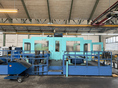 Koruyucu panelli endüstriyel mavi CNC makinesi, önden görünüm, alet deposu ve yan tarafta atık toplama arabası.
