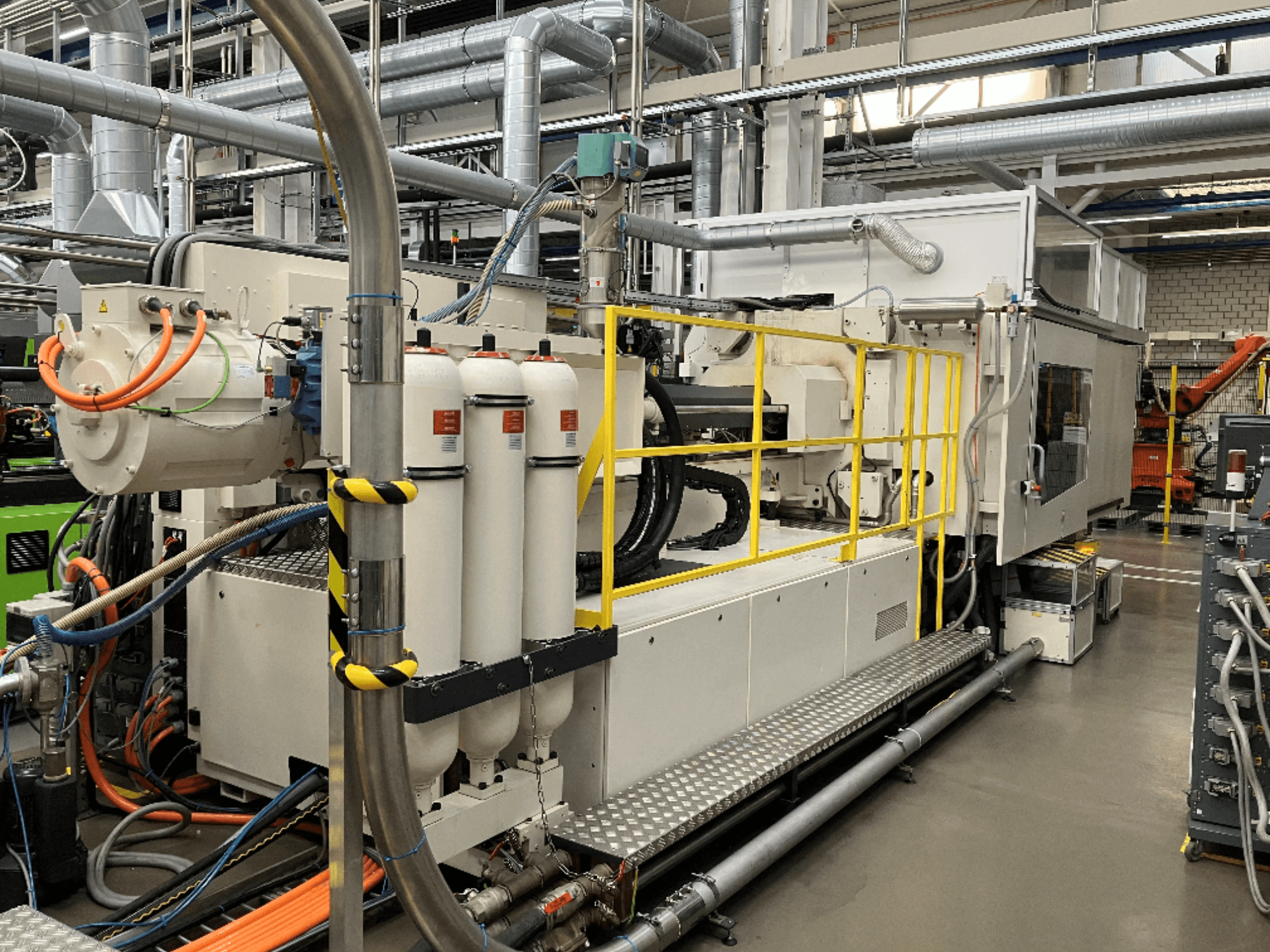 Beyaz ve gri gövdeli, çok sayıda hortumlu ve filtre tanklı endüstriyel makine; operasyonel kurulumu gösteren yandan görünüm.