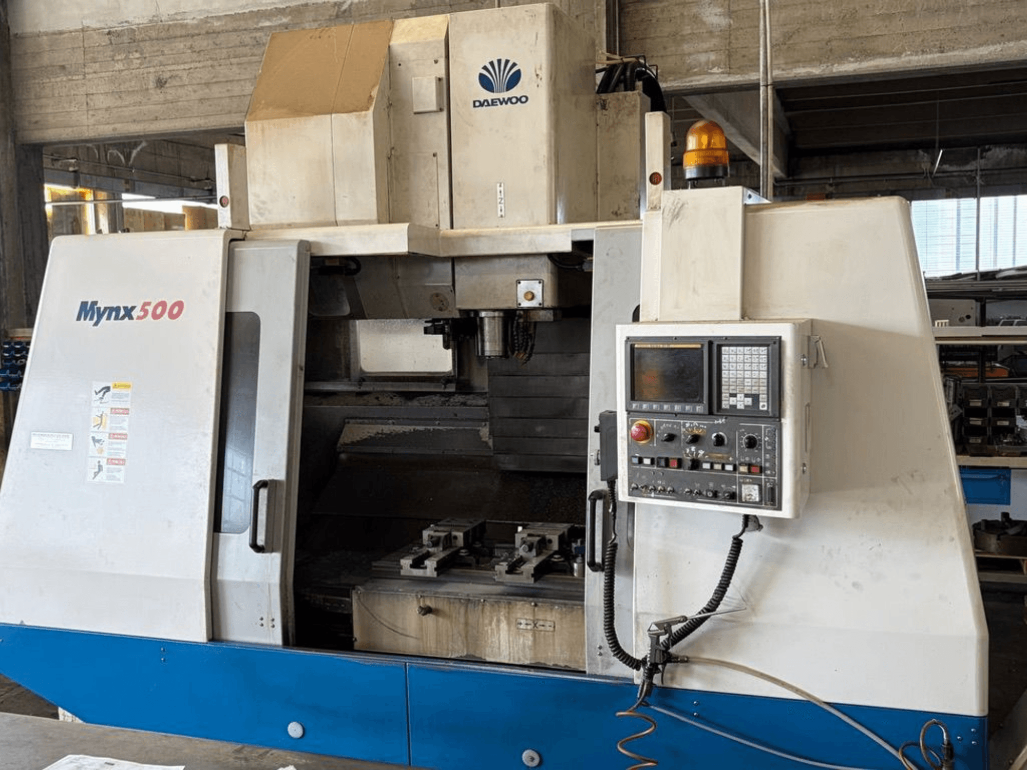 Önden gösterilen DAEWOO Mynx 500 dikey işleme merkezi; içinde bir kontrol paneli ve takım tutucu bulunmaktadır.