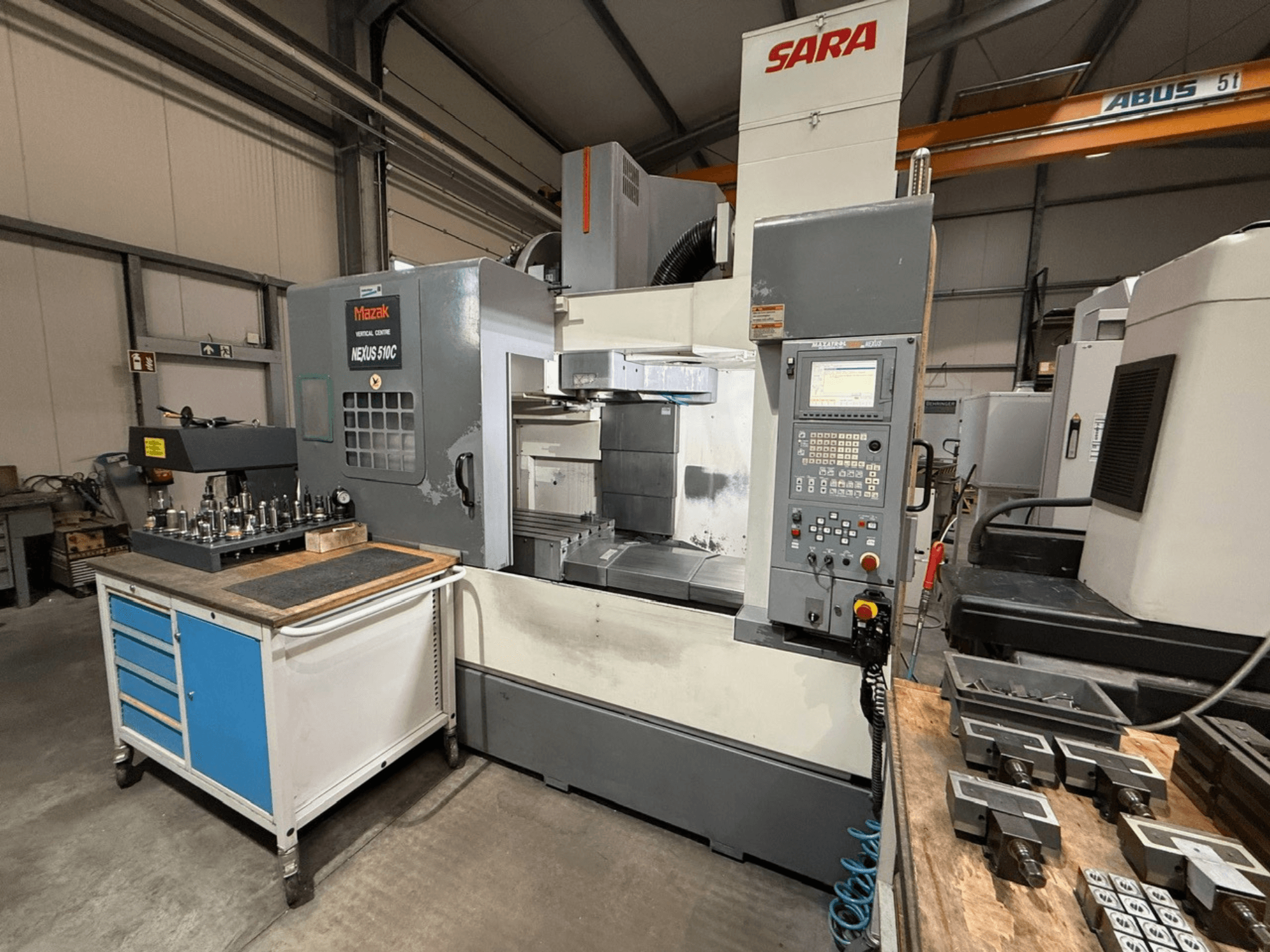 Mazak Nexus 510C dikey işleme merkezi, önden görünüm, bir araba üzerinde takımlar; SARA markası görülebilir; teknik kontroller gösterilmiştir.