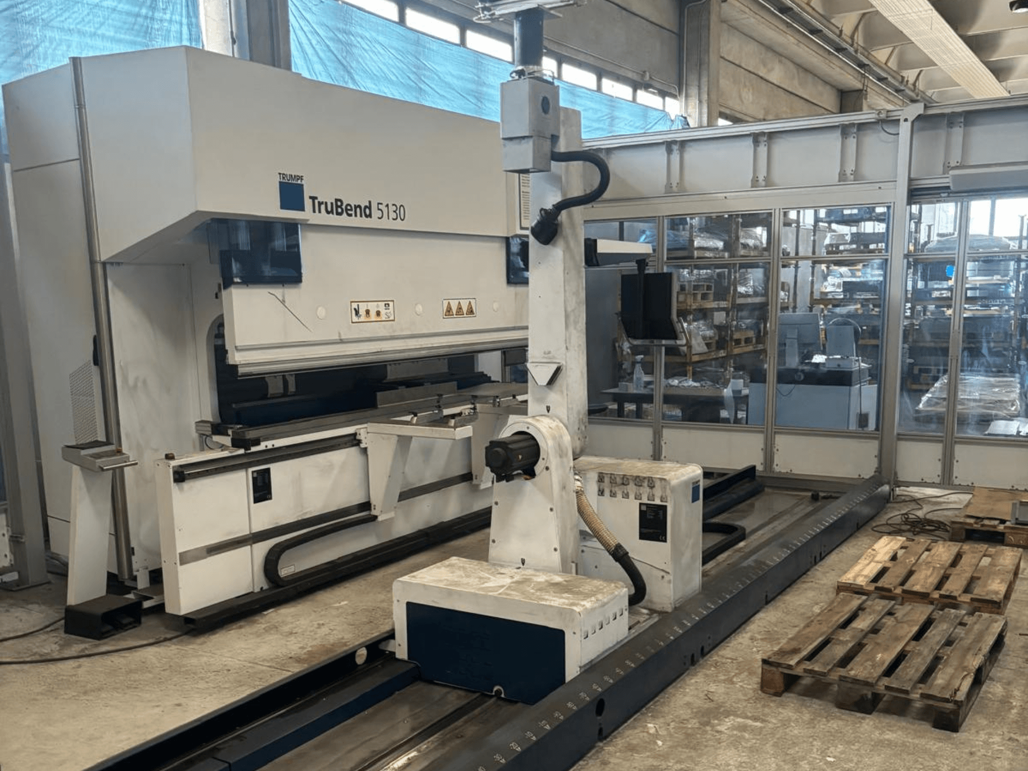 Trumpf TruBend 5130 bükme makinesi, önden görünüm, kontrol paneli ve paletlerle birlikte fabrika ortamında.