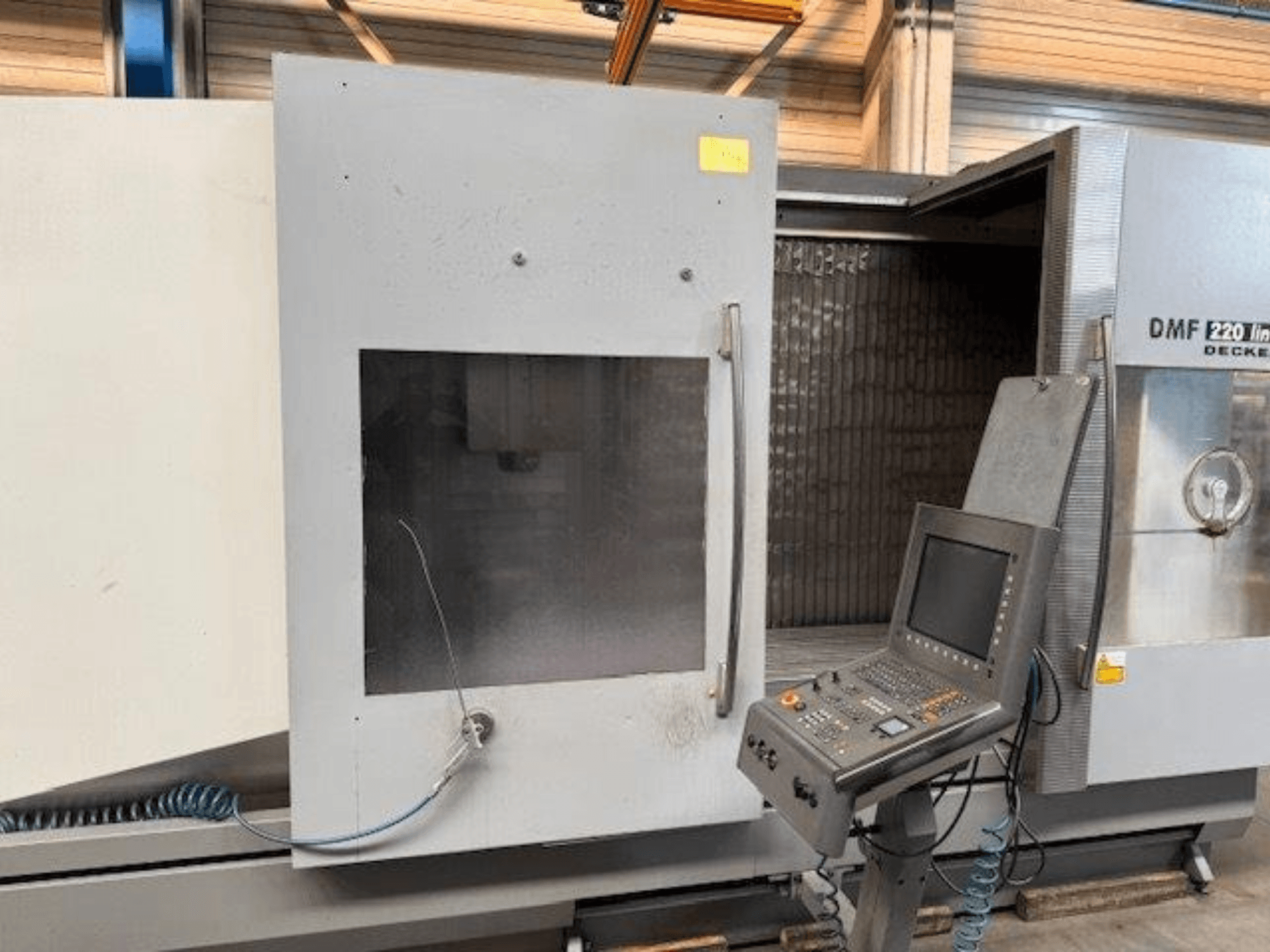 DECKEL MAHO DMF 220 Lineer dik işleme merkezinin önden görünümü, kontrol paneli ve açık makine kapısı.