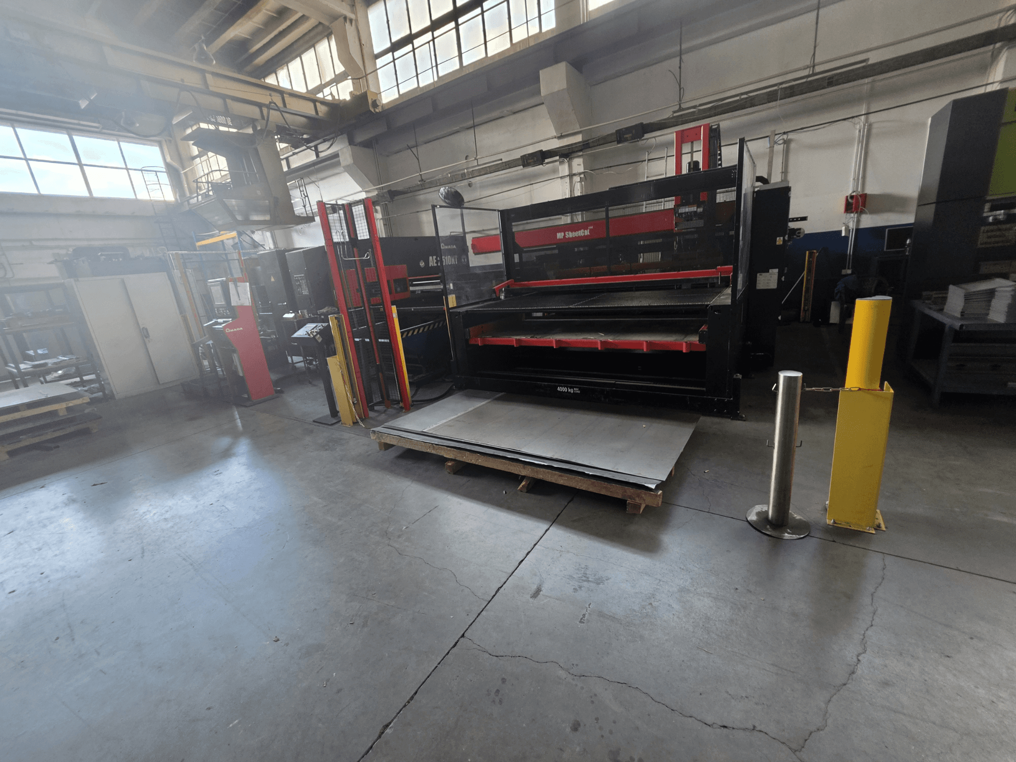 Depoda bulunan AMADA AE-2510NT CNC delme makinesi, yandan çekilmiş bir fotoğrafta makinenin kurulum durumu ve metal levhalar görülüyor.
