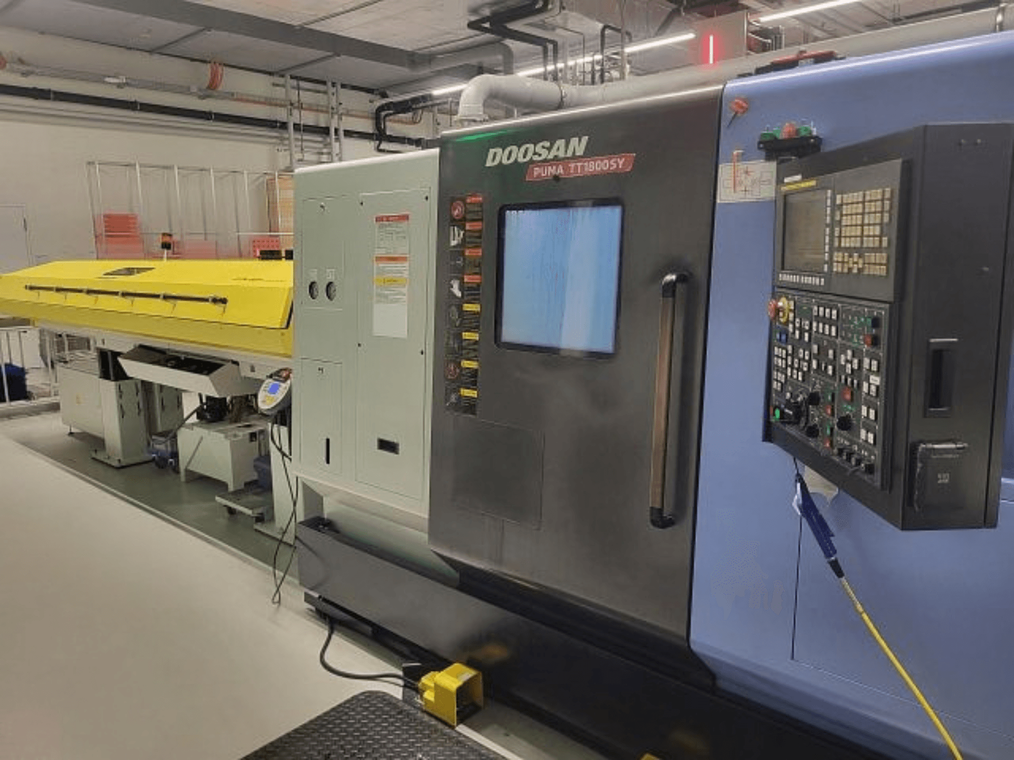 DOOSAN PUMA TT 1800 SY torna-freze merkezi, kontrol paneli ve sarı kapak ile birlikte önden görünüm, endüstriyel ortam.