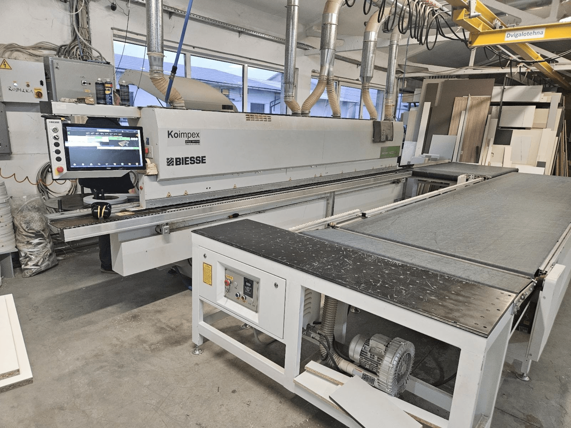 BIESSE Akron 1440 Atölyede bir kenar bantlama makinesi, kontrol panelini ve konveyör bandını gösteren yandan görünüm.