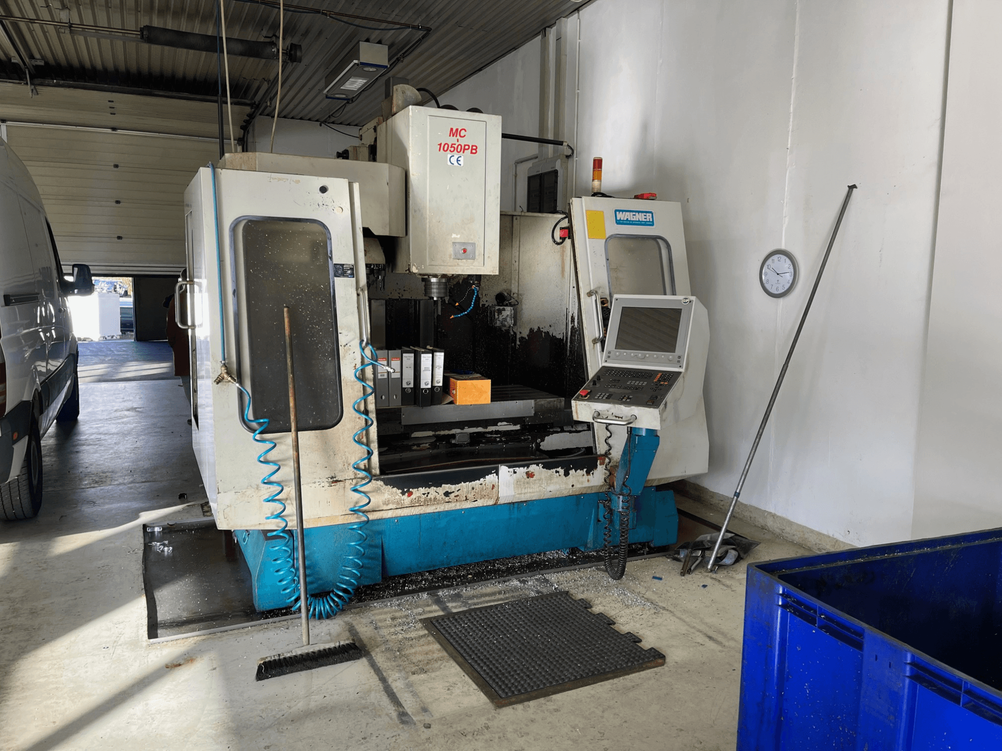 WAGNER MC 1050PB CNC makinesi atölyede, önden görünüm, kontrol paneli ve çalışma alanı ile; mavi hava hortumu ve temizleme aletleri görülebilir.