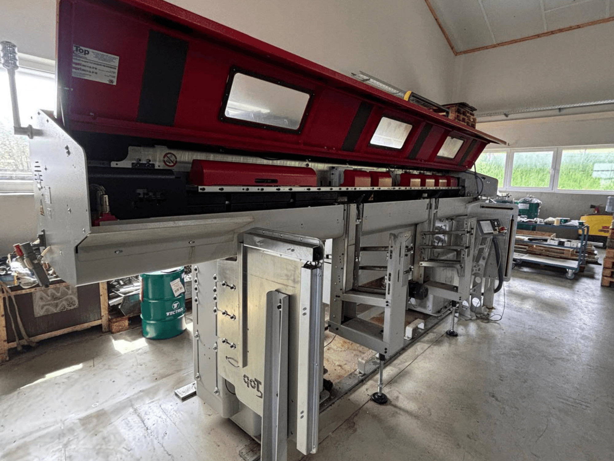 TOP Automazioni Top Loader ETL 10-75 modelinin yandan görünümü; kırmızı üst kısmı ve karmaşık mekanik bileşenleri göze çarpıyor.