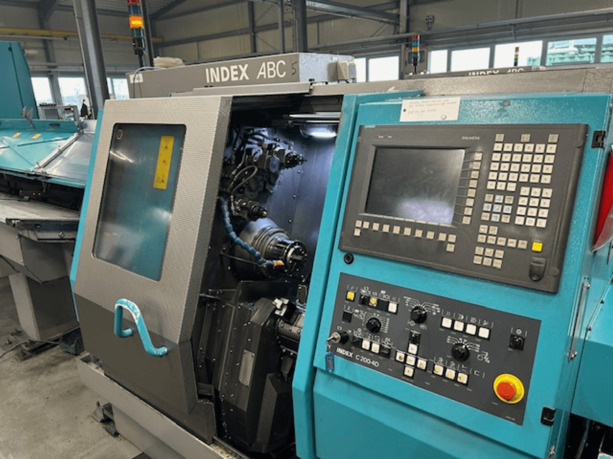 INDEX C200-AD CNC torna tezgahının kontrol paneli, görünür iç bileşenleri ve güvenlik özellikleri ile önden görünümü.