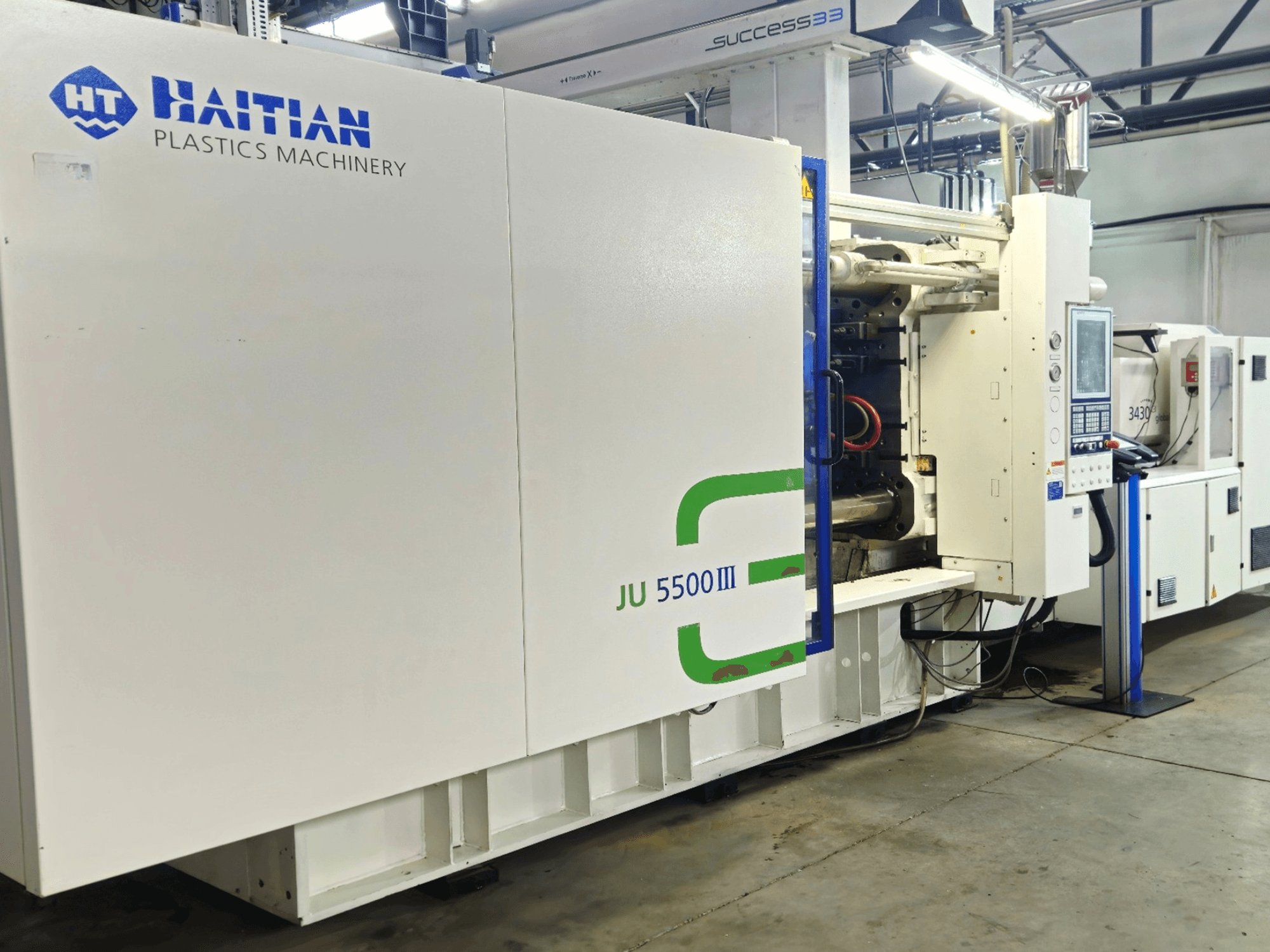 Fabrika ortamında Haiti JU 5500III plastik makinesi, kontrol paneli ve üretim alanını gösteren önden görünüm.