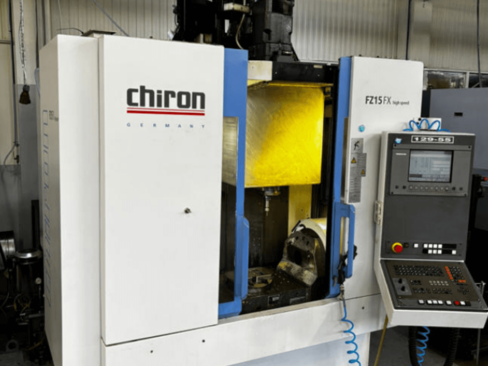 CHIRON FZ 15FX dikey işleme merkezi, önden görünüm; kontrol paneli ve takımların bulunduğu işleme alanı açıkça görülmektedir.