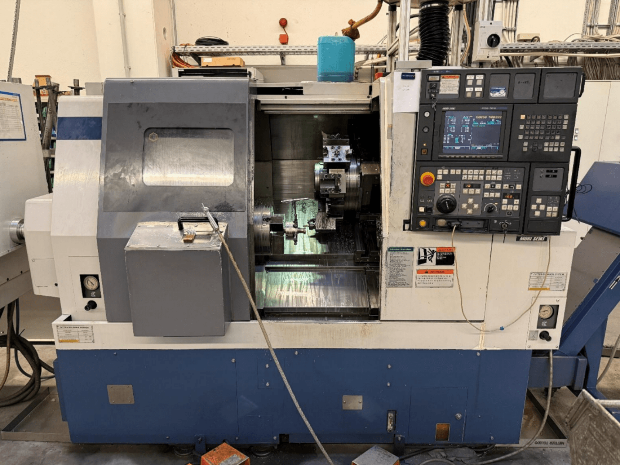 MORI SEIKI SL-250ASMC Torna-Freze Merkezi; kontrol paneli ve iş parçası mandreninin çalışır durumda olduğu ön görünüm.