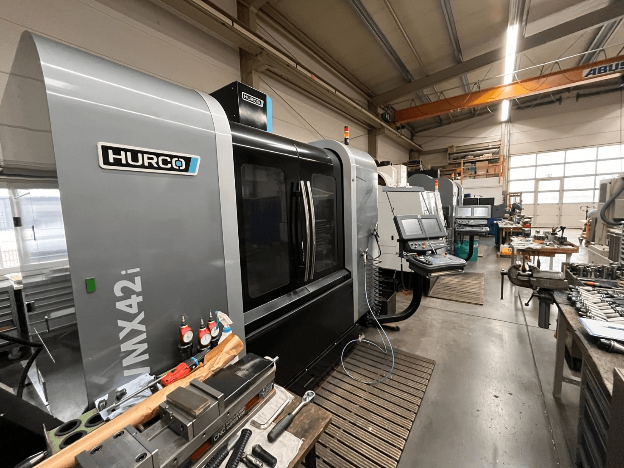 Hurco VMX42i CNC makinesi bir atölyede, önden görünüm. Kontrol paneli, gri gövde ve endüstriyel çevre özellikleri.