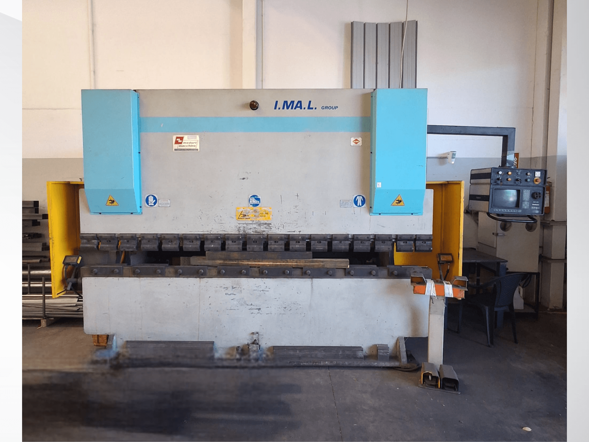 IMAL E3A 100/33 Abkant Presinin önden görünümü; kontrol paneli, bükme aletleri ve güvenlik işaretleri görülmektedir.