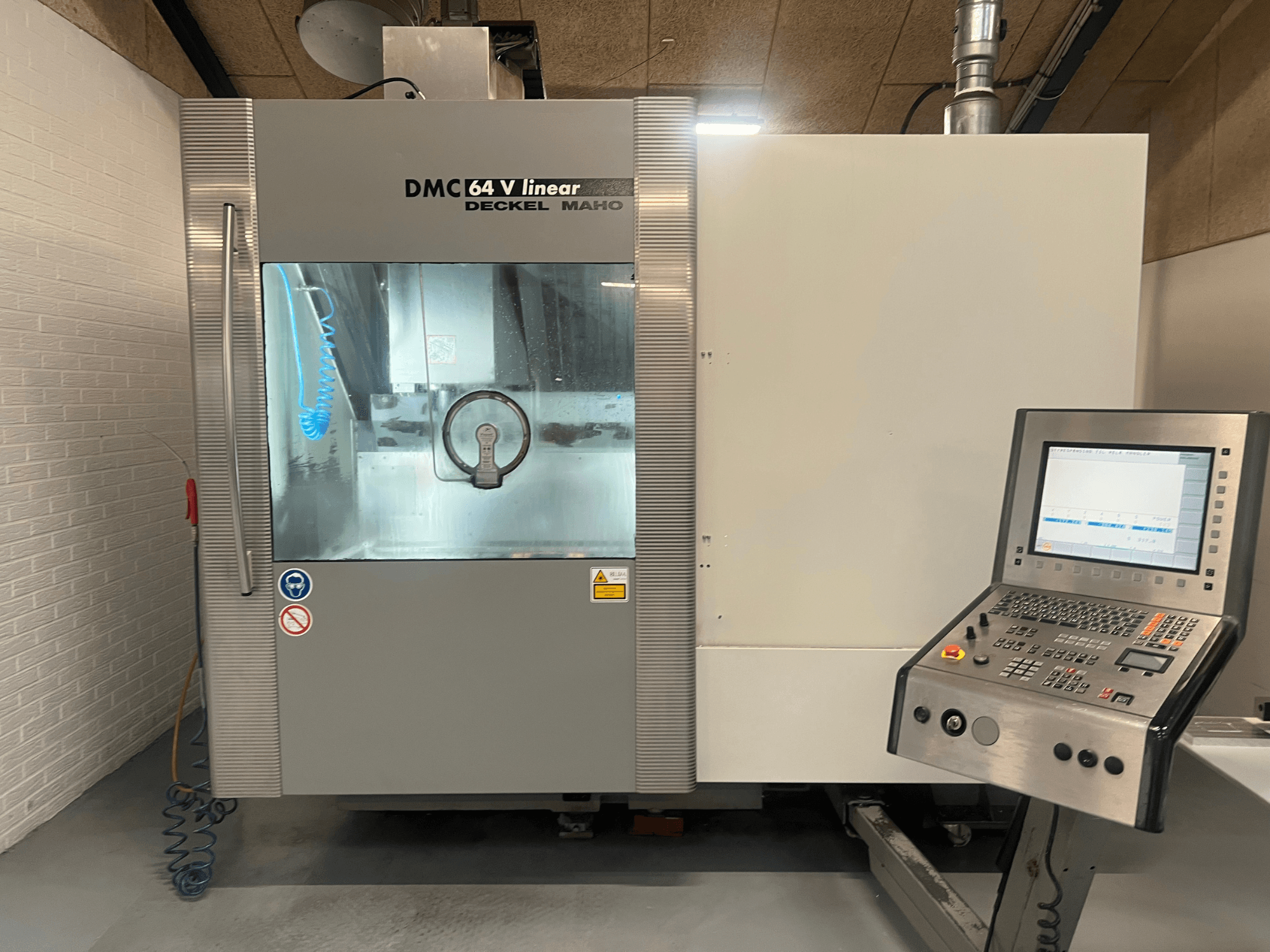Deckel Maho'dan DMC 64 V Linear, kontrol paneli ve soğutucu nozulu görünen CNC işleme merkezinin önden görünümü.