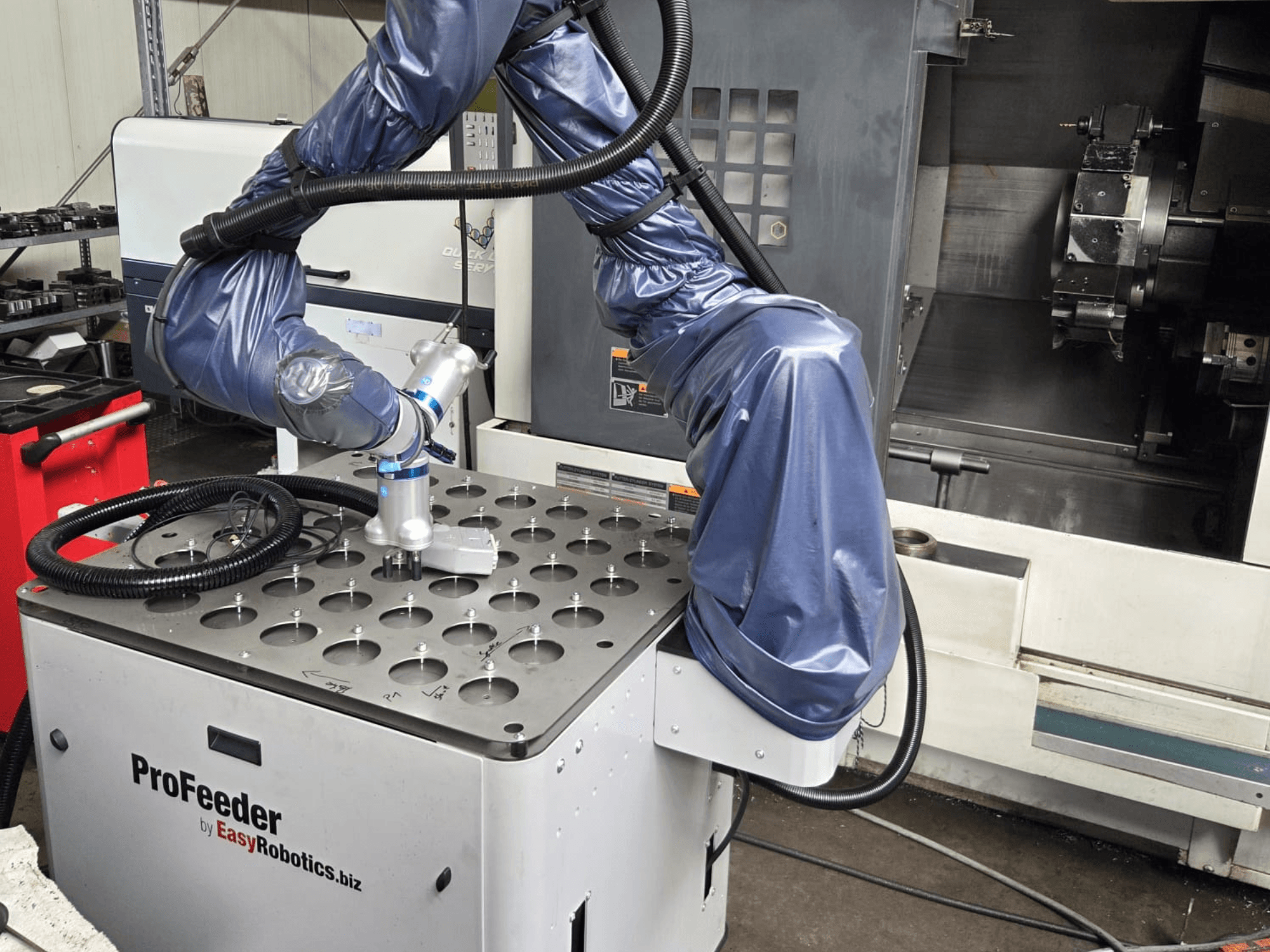 İşbirlikçi robot EASYROBOTICS ProFeeder'ın önden görünümü, delikli metal bir masanın üzerine yerleştirilmiş robotik kol.