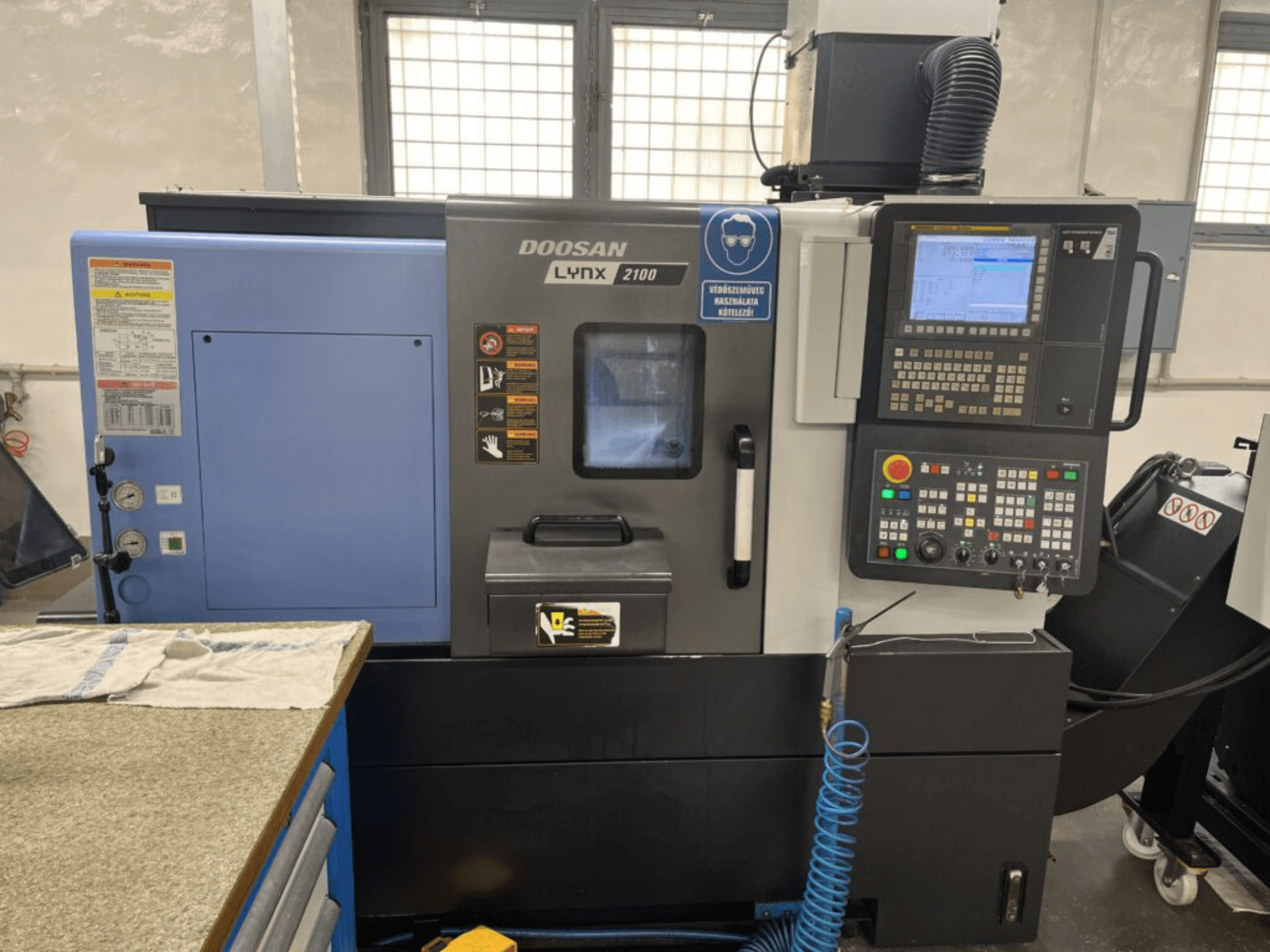 DOOSAN Lynx 2100A yatay torna makinesi, kontrol paneli, operatör arayüzü ve makine özelliklerini gösteren önden görünüm.