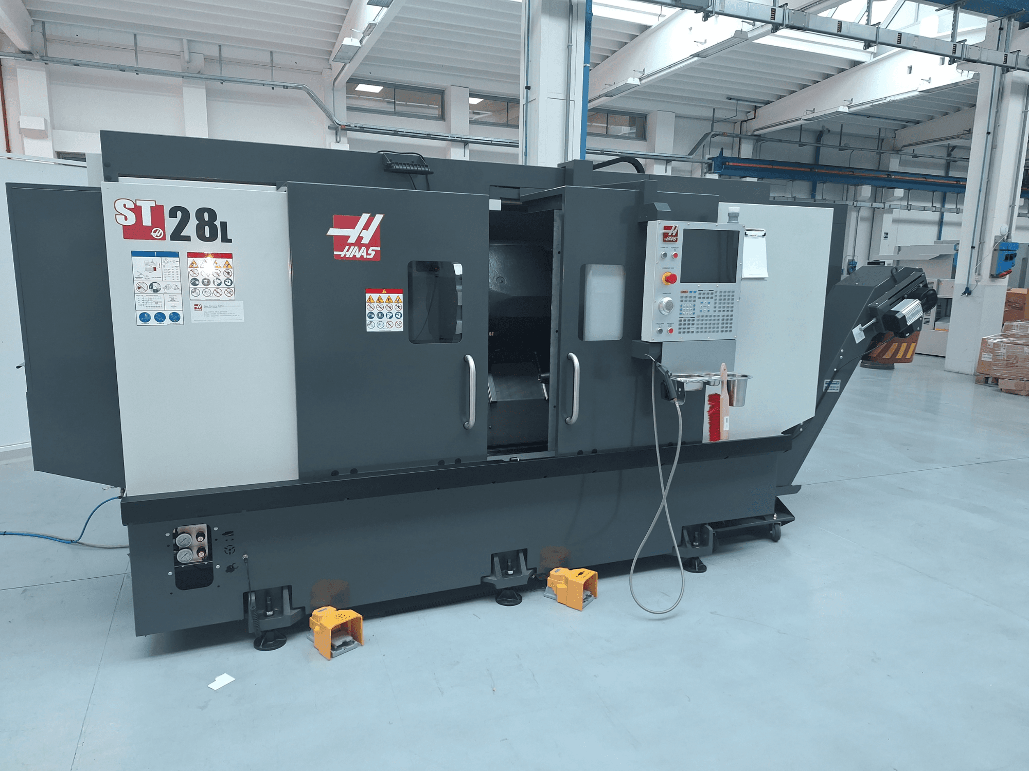 Haas ST-28L yatay torna tezgahının yan görünümü; kontrol paneli, çalıştırma düğmeleri ve güvenlik etiketleri görülmektedir.