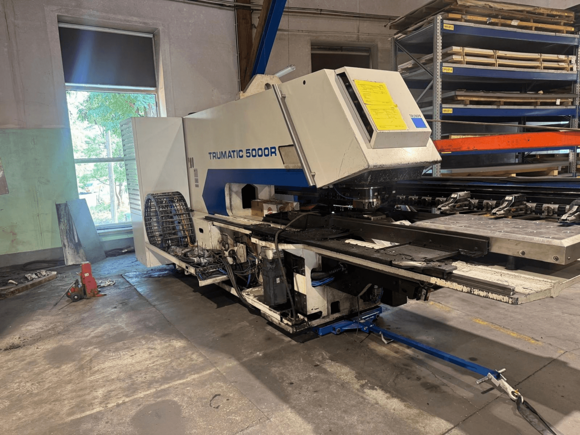 Bir atölyede bulunan TRUMPF TRUMATIC 5000R CNC delme makinesinin, kontrol panellerini ve delme alanını gösteren önden görünüşü.