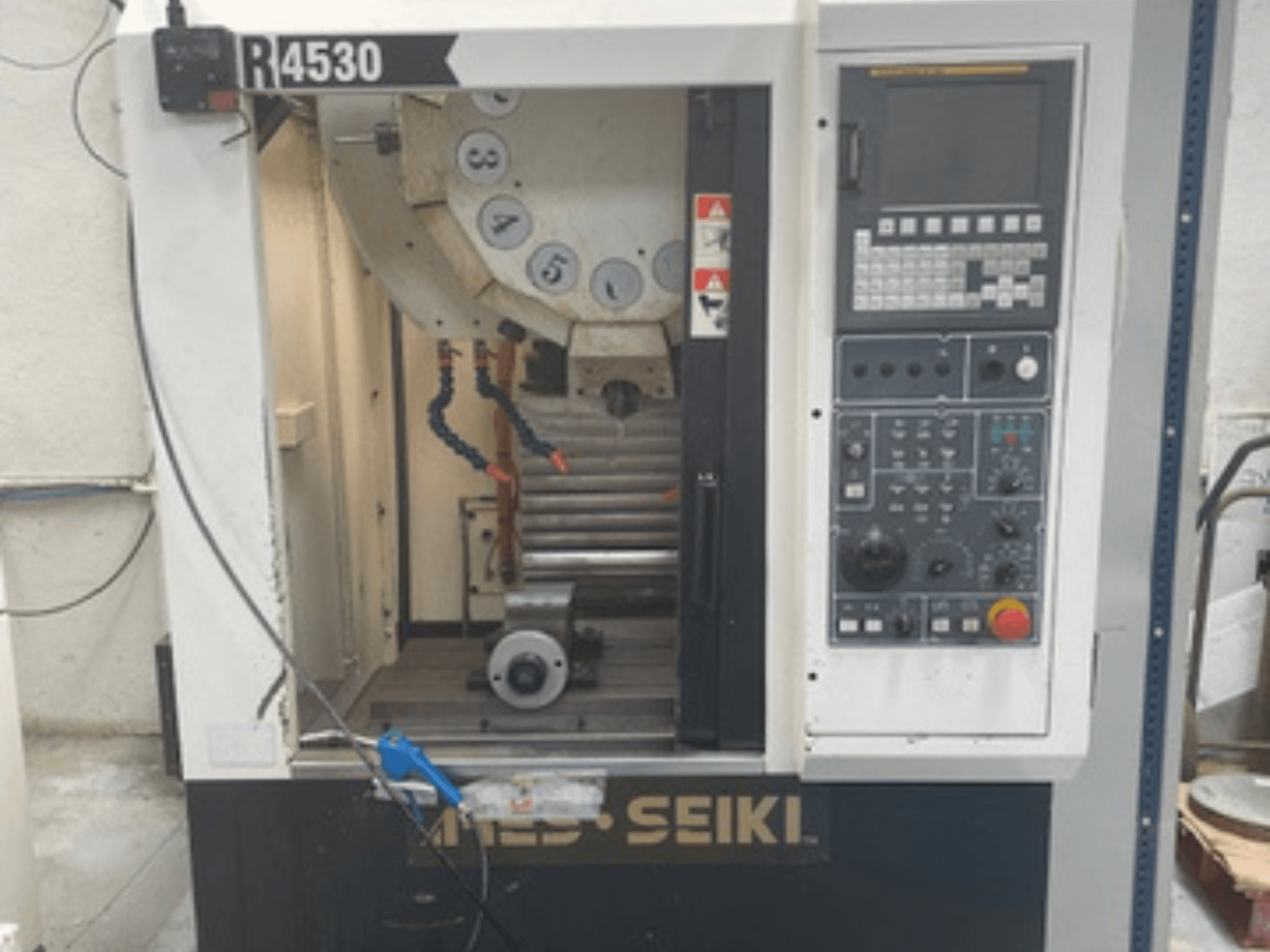 Dikey işleme merkezi ARES-SEIKI R4530, kontrol paneli ve iş mili ve soğutma sistemi ile çalışma alanını gösteren önden görünüm.