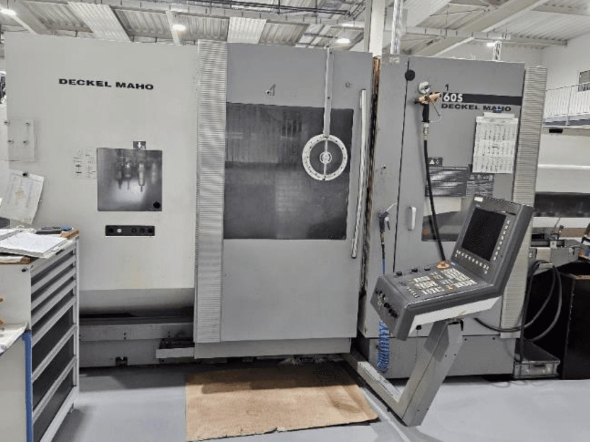 DECKEL MAHO 60S CNC makinesinin önden görünümü, kontrol paneli, aletler görünür, bir atölye ortamında.