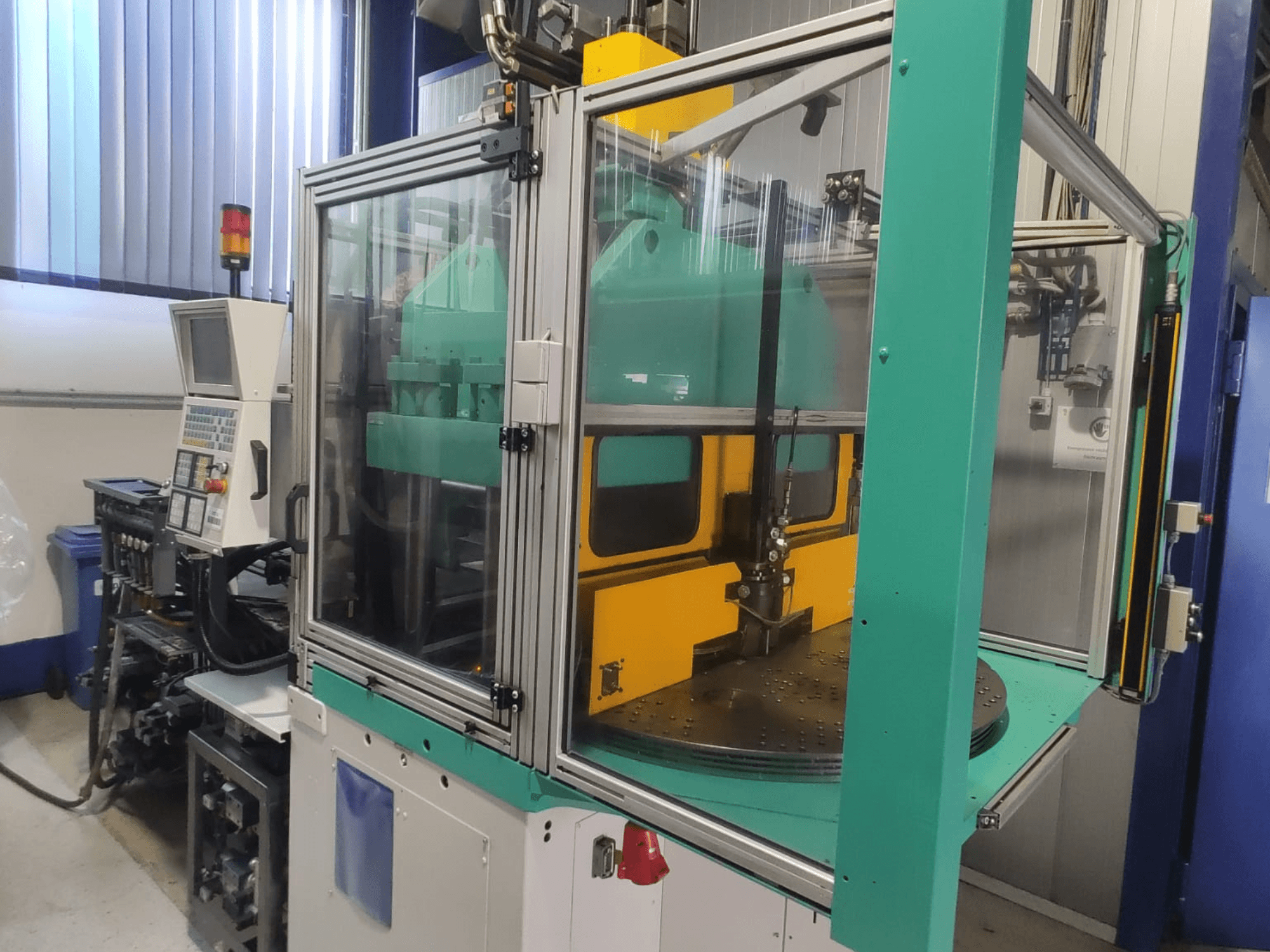 Arburg 1200 TS 800-60-350 dikey enjeksiyon kalıplama makinesi; kontrol paneli ve güvenlik muhafazasını gösteren önden görünüm.