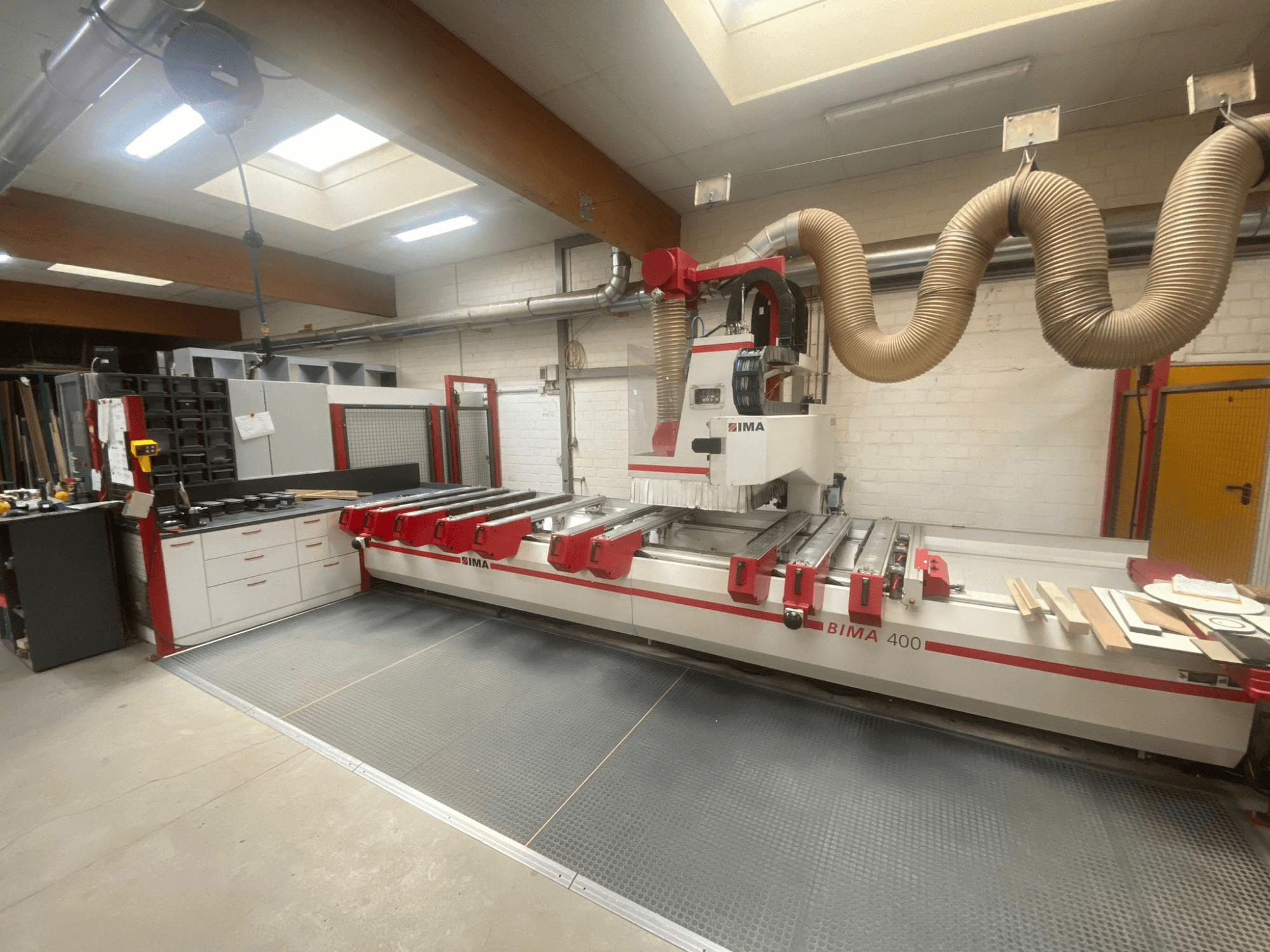 BIMA 400 CNC makinesi önden bakıldığında kırmızı ve beyaz bir tasarıma ve toz emme sistemine sahiptir.