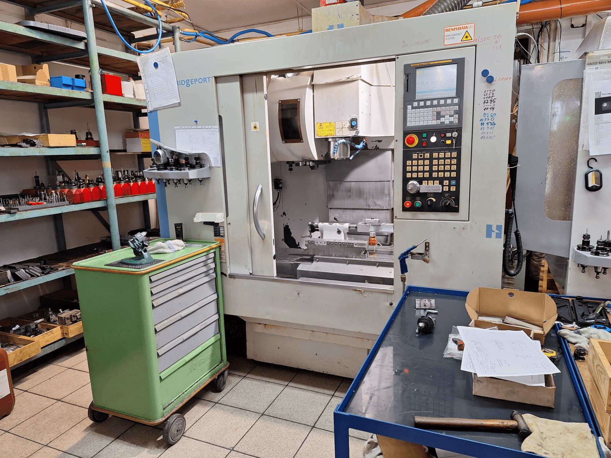 Bir atölye ortamında, kontrol paneli, takımlar ve raflarla birlikte Hardinge Bridgeport GX 710 dikey işleme merkezinin önden görünümü.