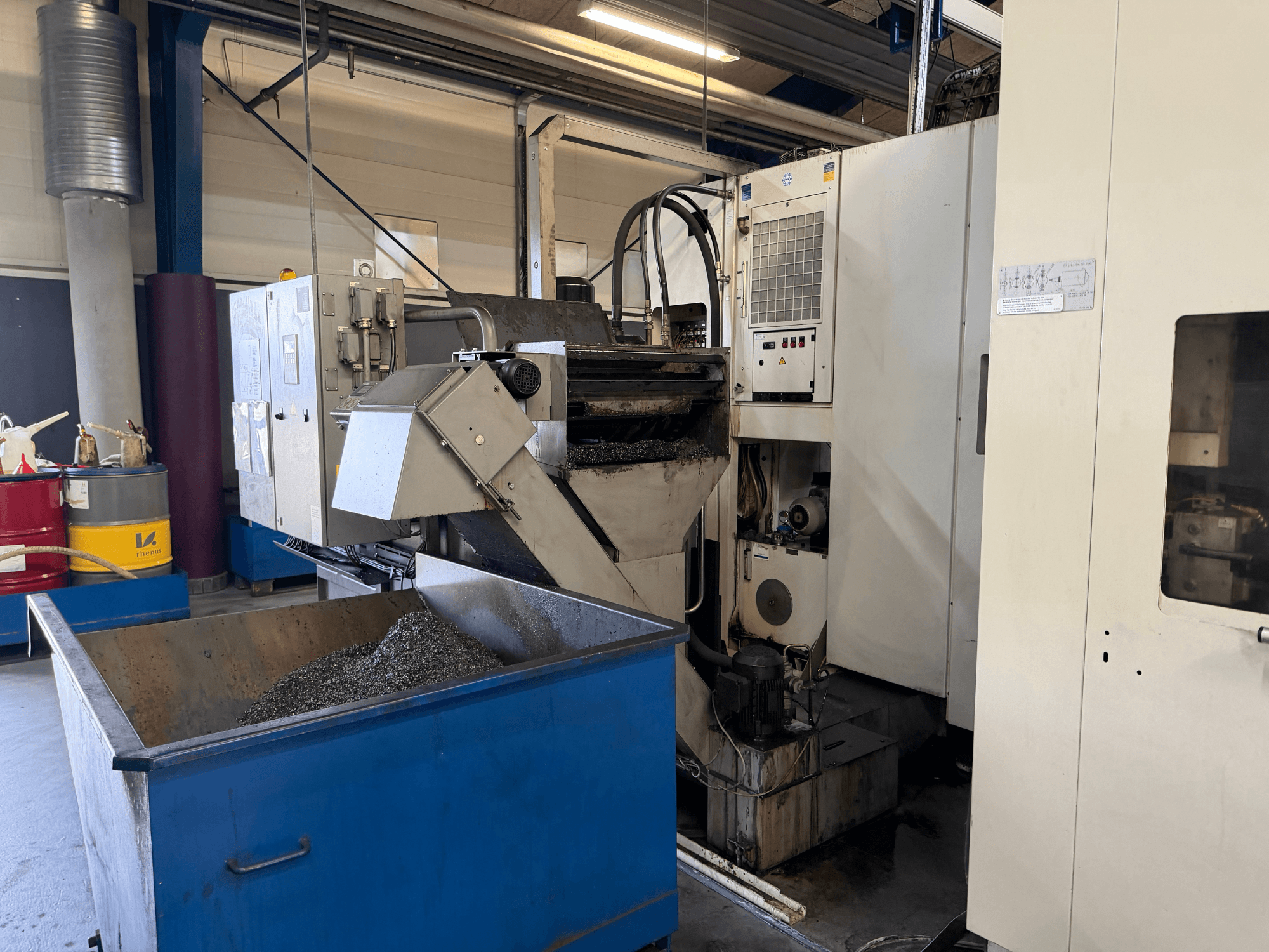 Metal soğutma sıvısı geri dönüşüm kutusu ve kontrol paneli görünen HELLER MCH 250 yatay işleme merkezinin önden görünümü.