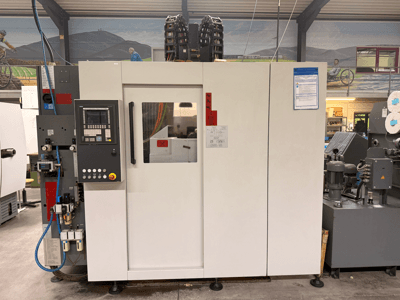 Kontrol panelli beyaz CNC işleme merkezi, önden görünüm, düğmeler ve dijital ekran, bir atölye ortamında.