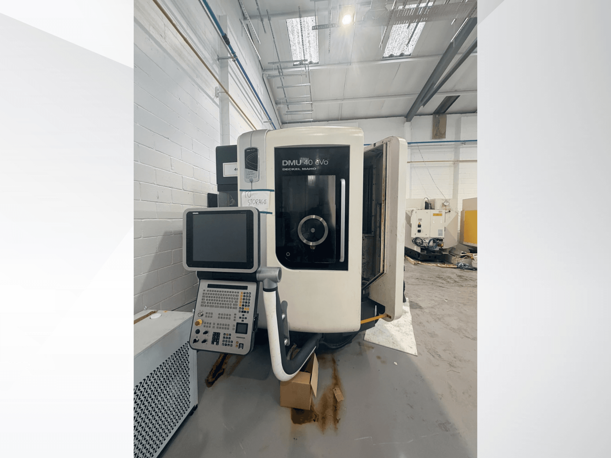 DMG DMU 40 evo dikey işleme merkezinin önden görünümü; kontrol paneli ve iş mili bölgesi gösterilirken arka planda çalışma alanı görülmektedir.