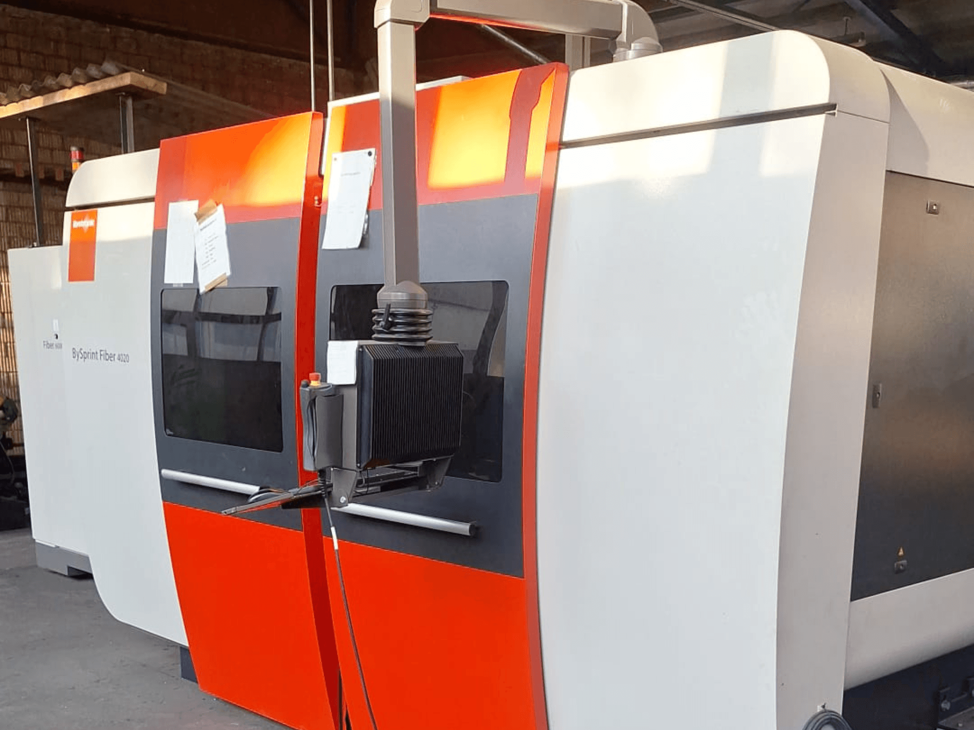 BySprint Fiber 4020 lazer kesim makinesi, yandan görünüm, kırmızı ve beyaz dış yüzey, ayrıntılı kontrol paneli görünür.